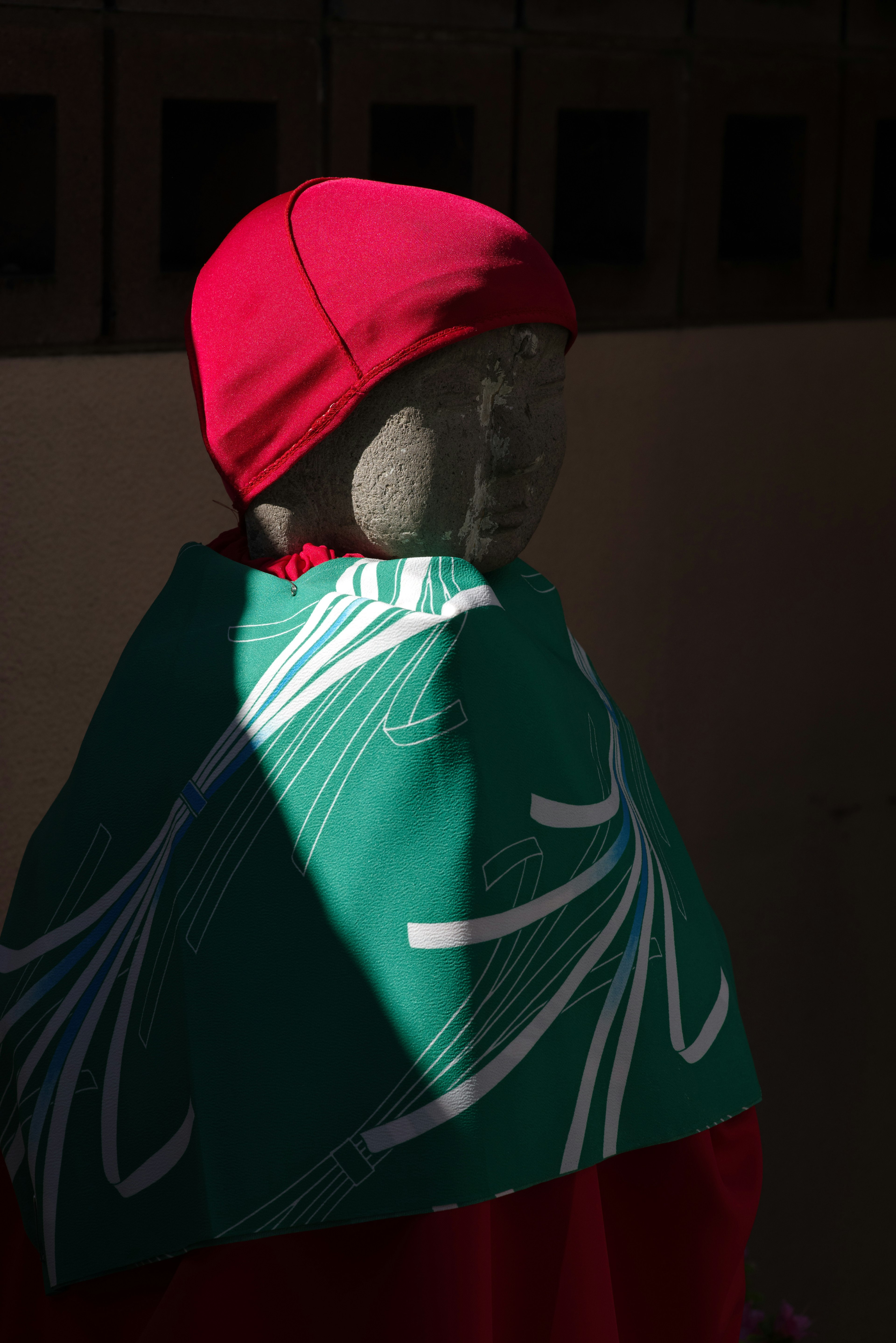 Stone statue wearing a red hat and green patterned cloth