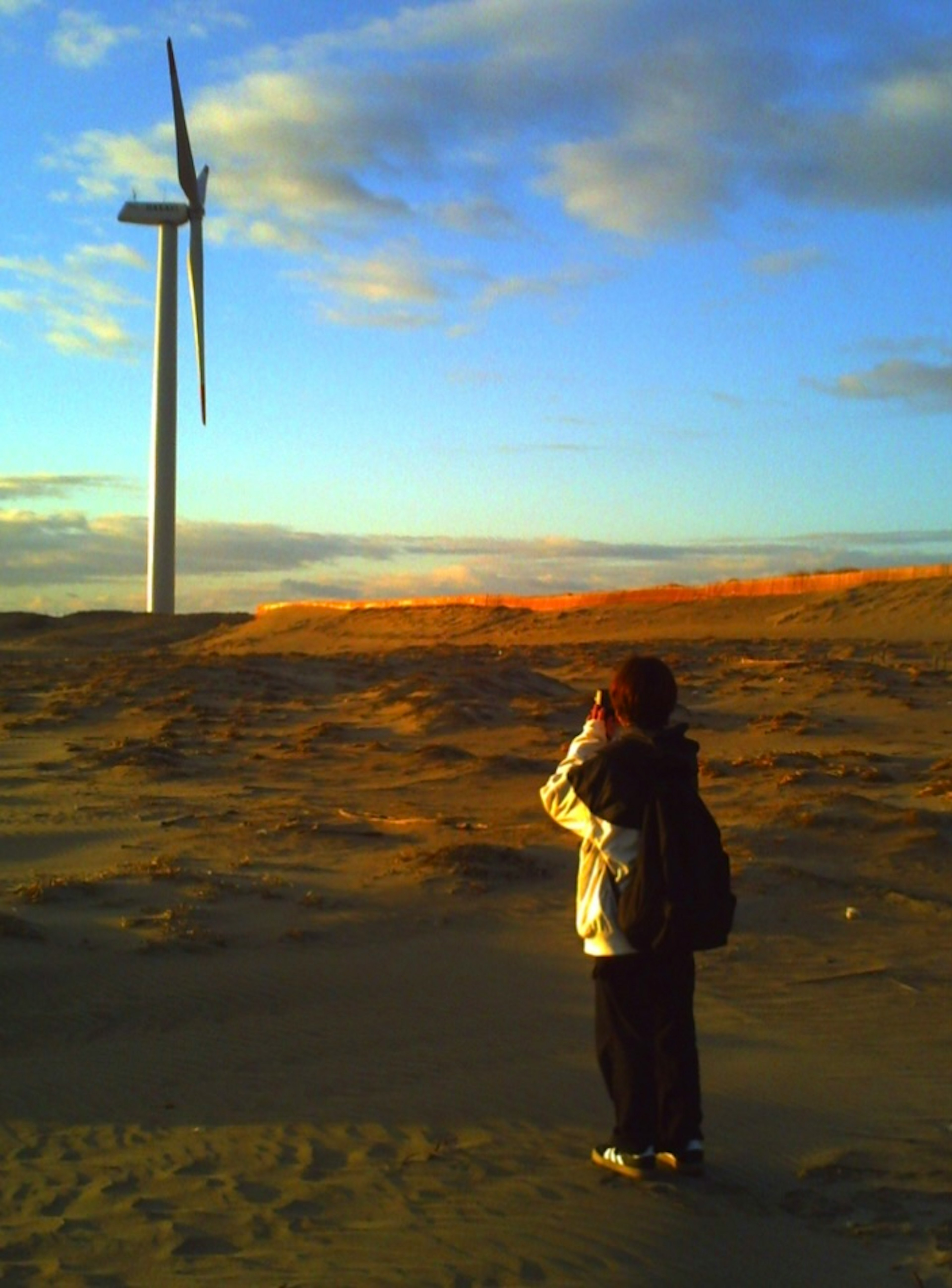 Person taking a photo in front of a wind turbine