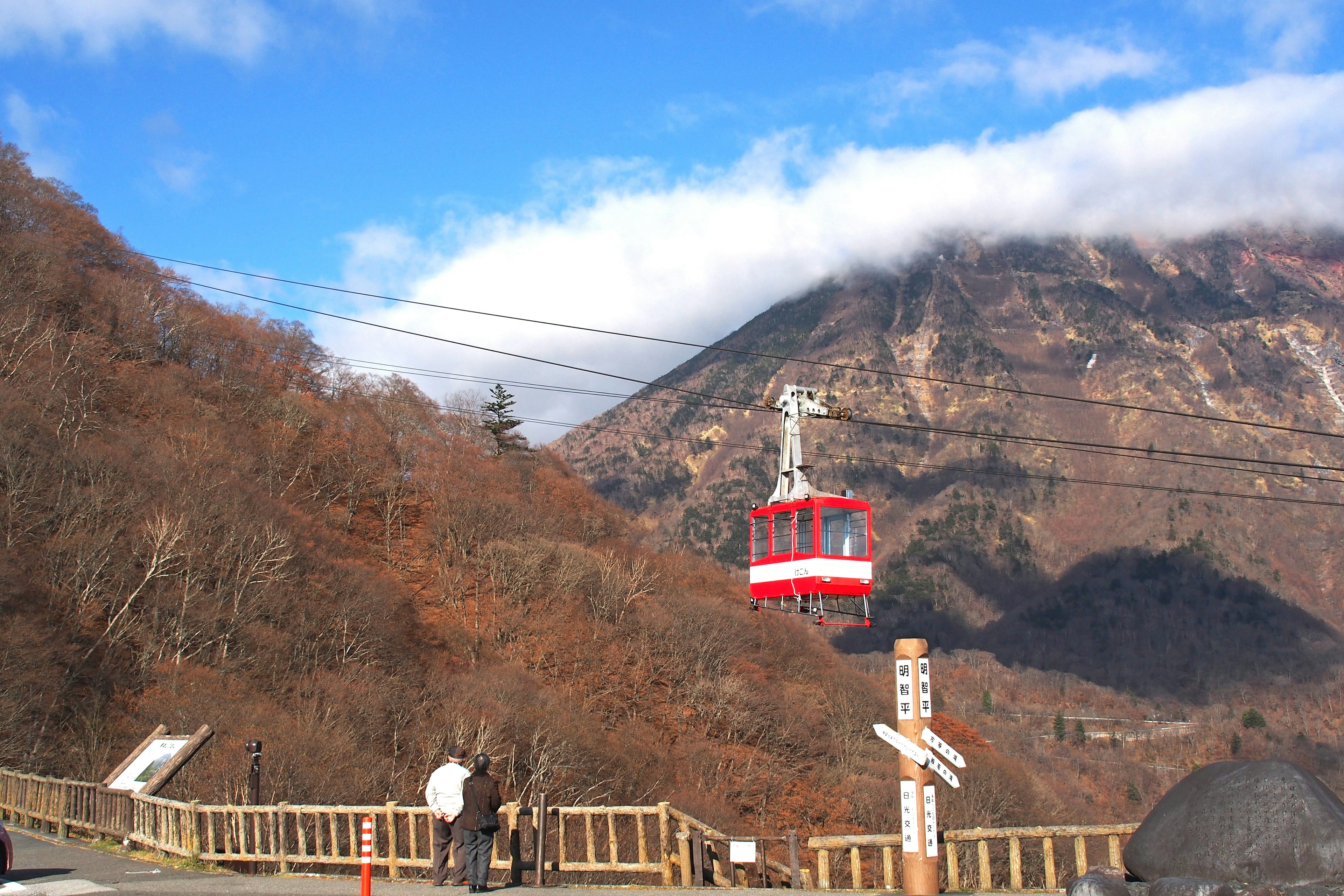 Rote Gondel, die in Richtung Berg fährt, unter klarem blauen Himmel