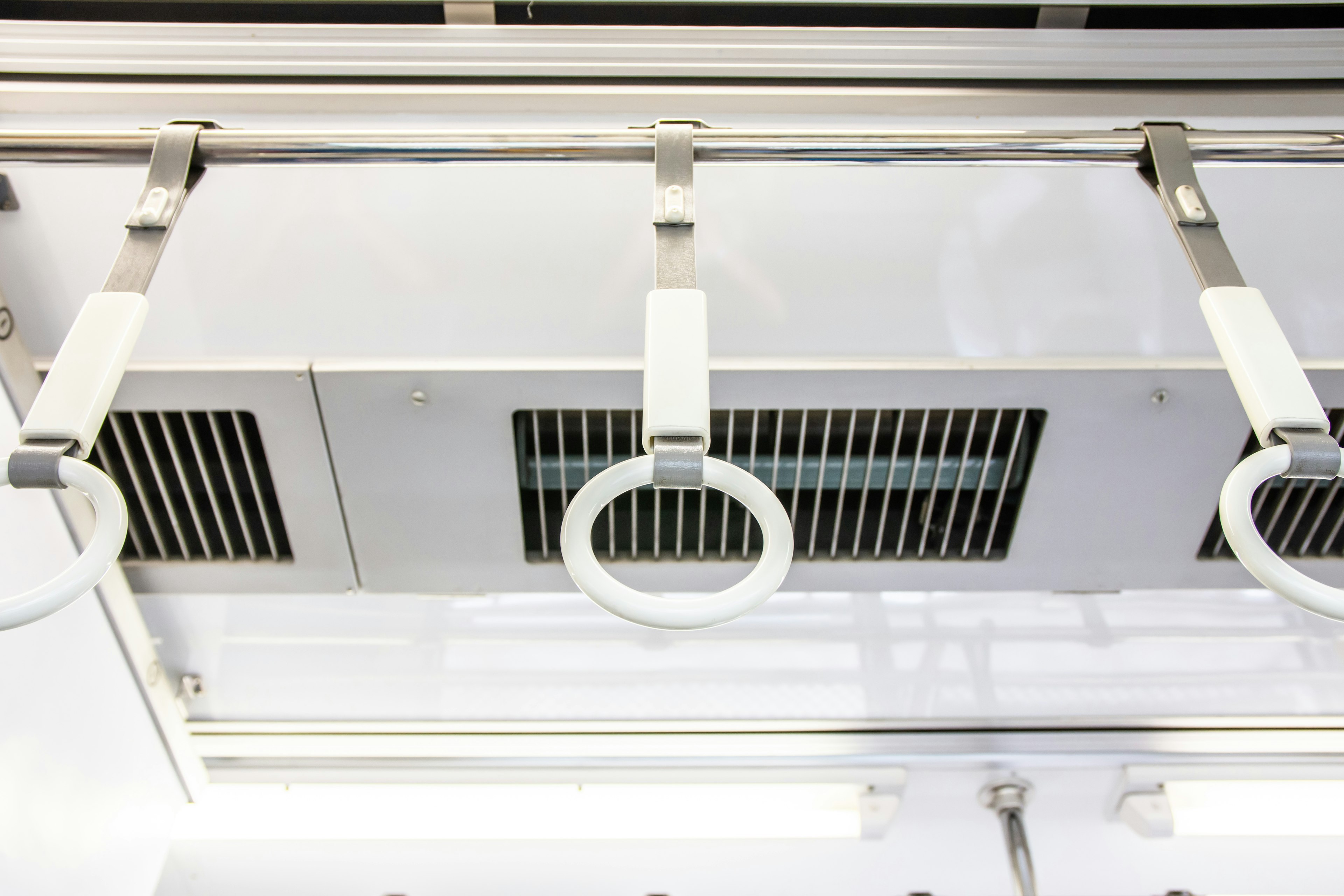 White handrails and ventilation grilles on the ceiling of a train car