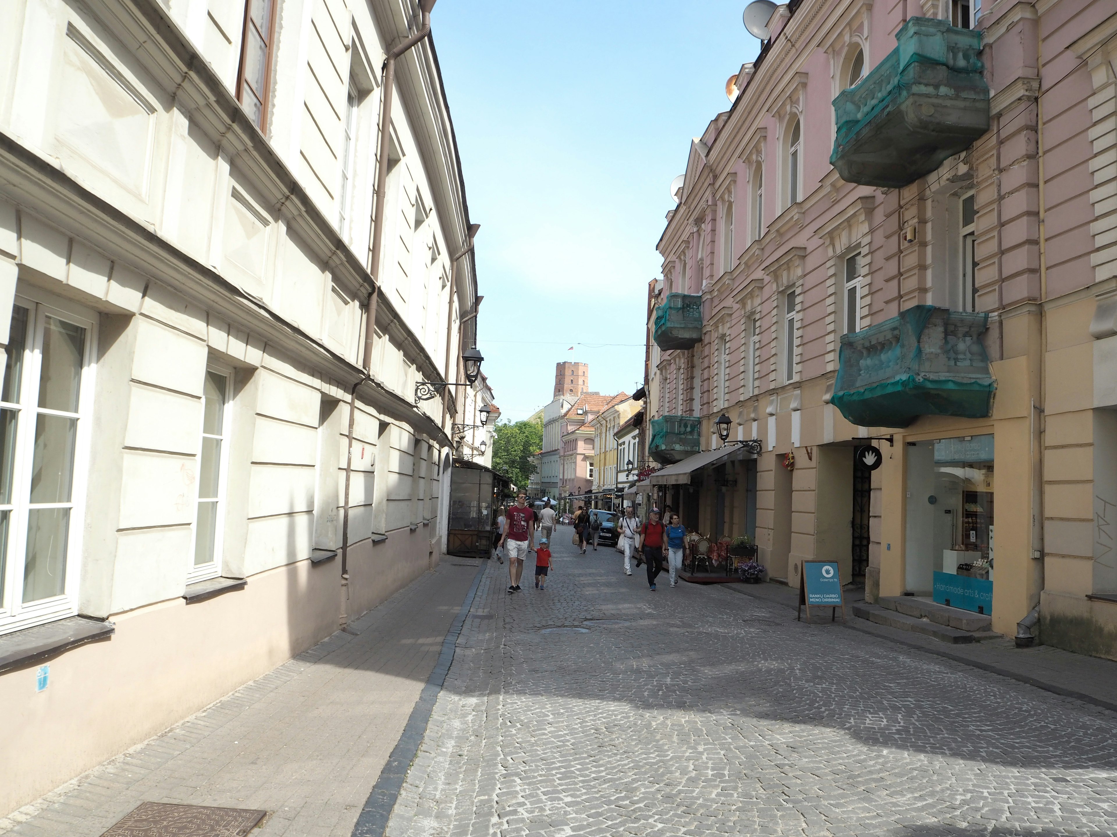 Kopfsteinpflasterstraße gesäumt von Gebäuden und gehenden Menschen