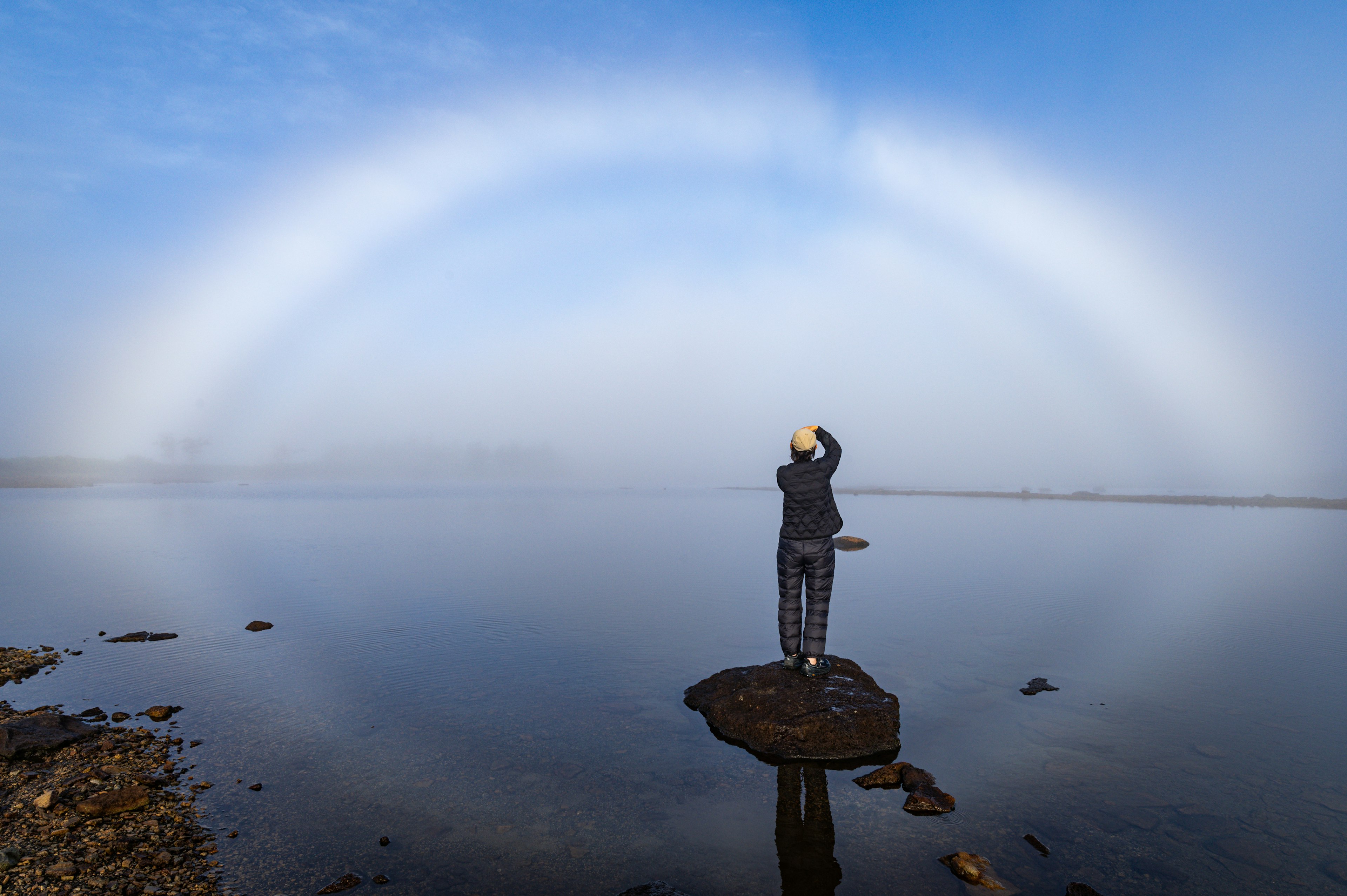 Persona in piedi su una roccia con un arcobaleno circolare nella nebbia