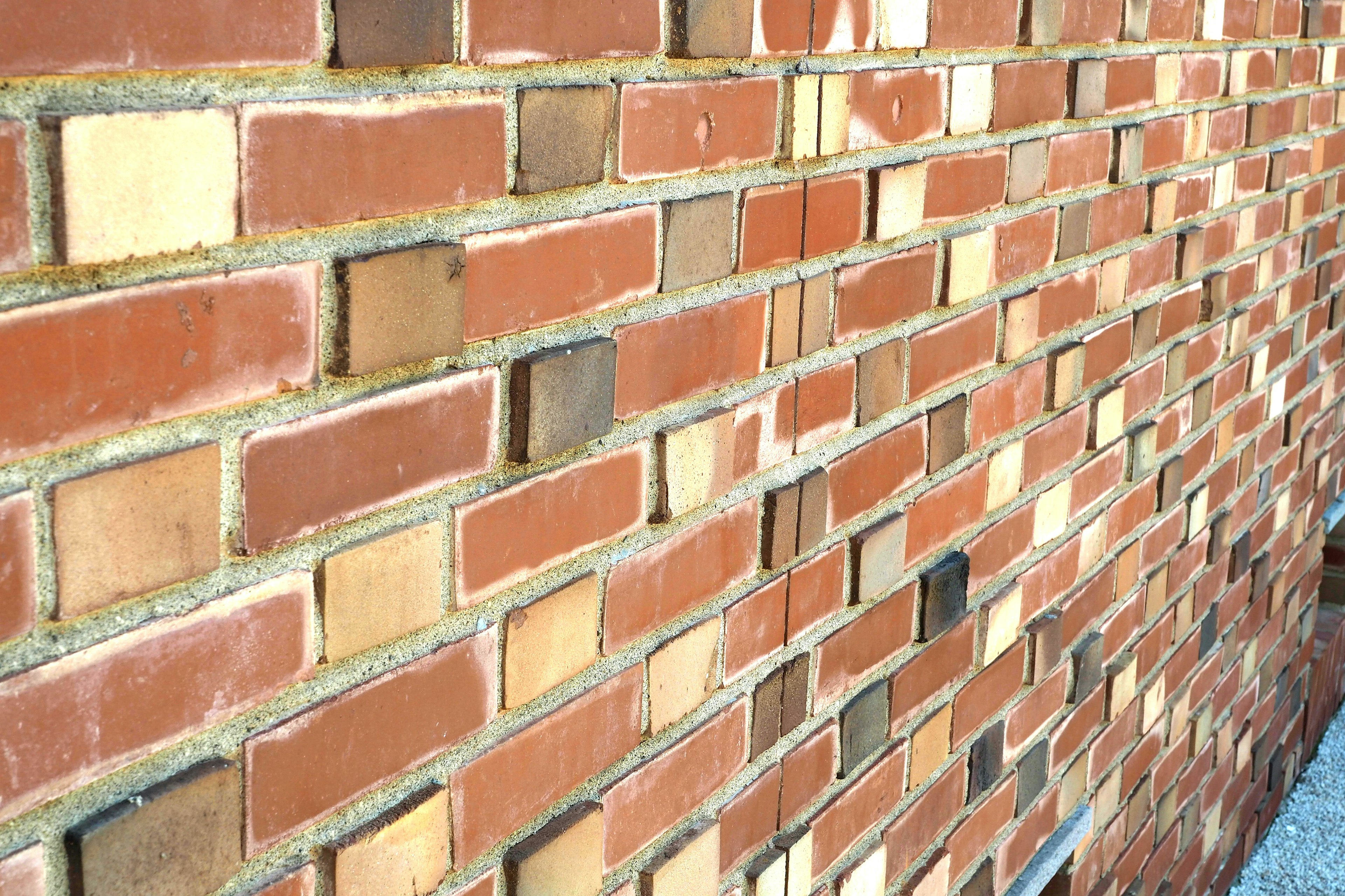 Primer plano de una pared de ladrillos rojos que muestra varias tonalidades y texturas de ladrillos