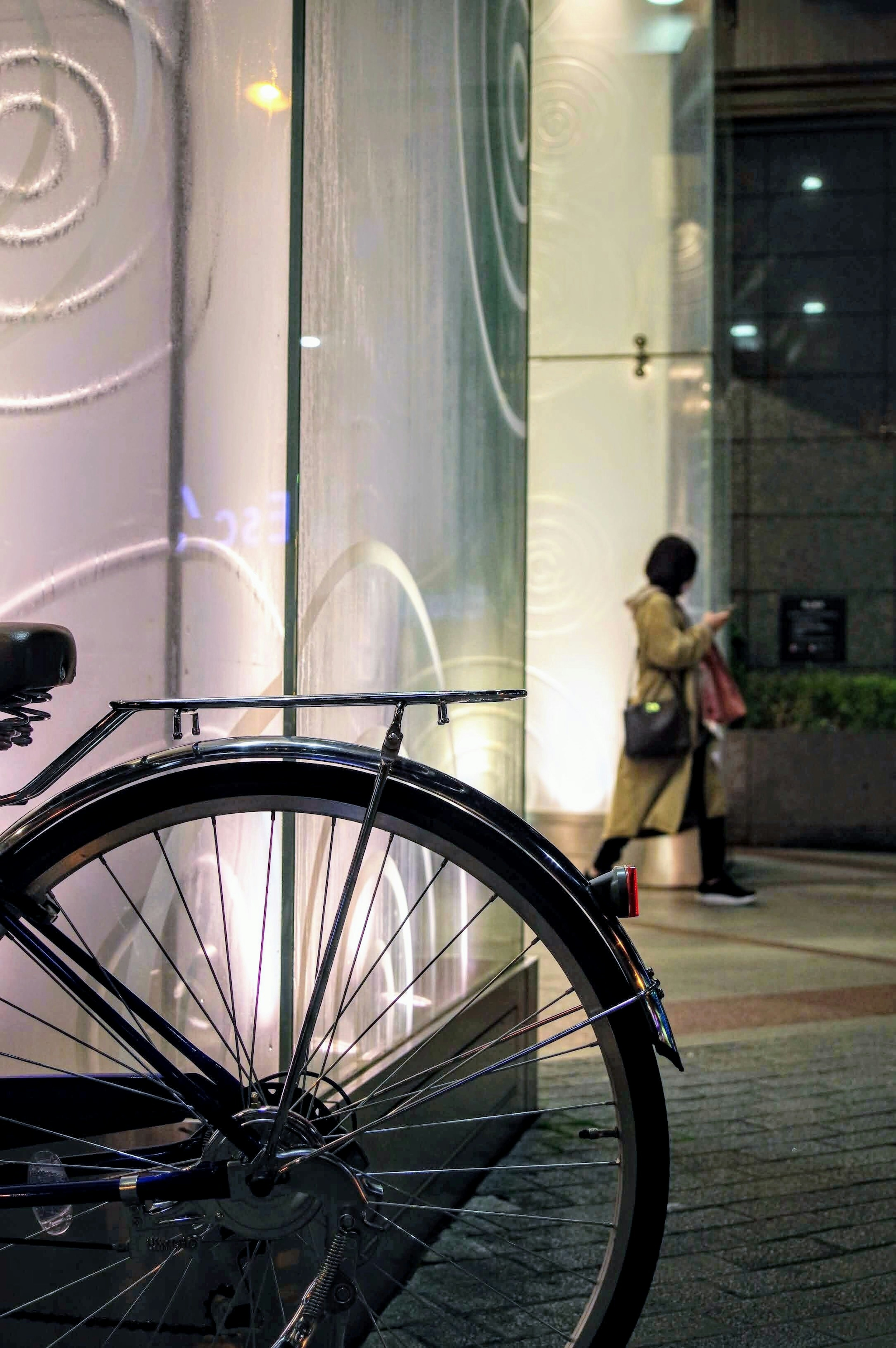 自転車の後ろに立つ女性と光る壁のデザイン