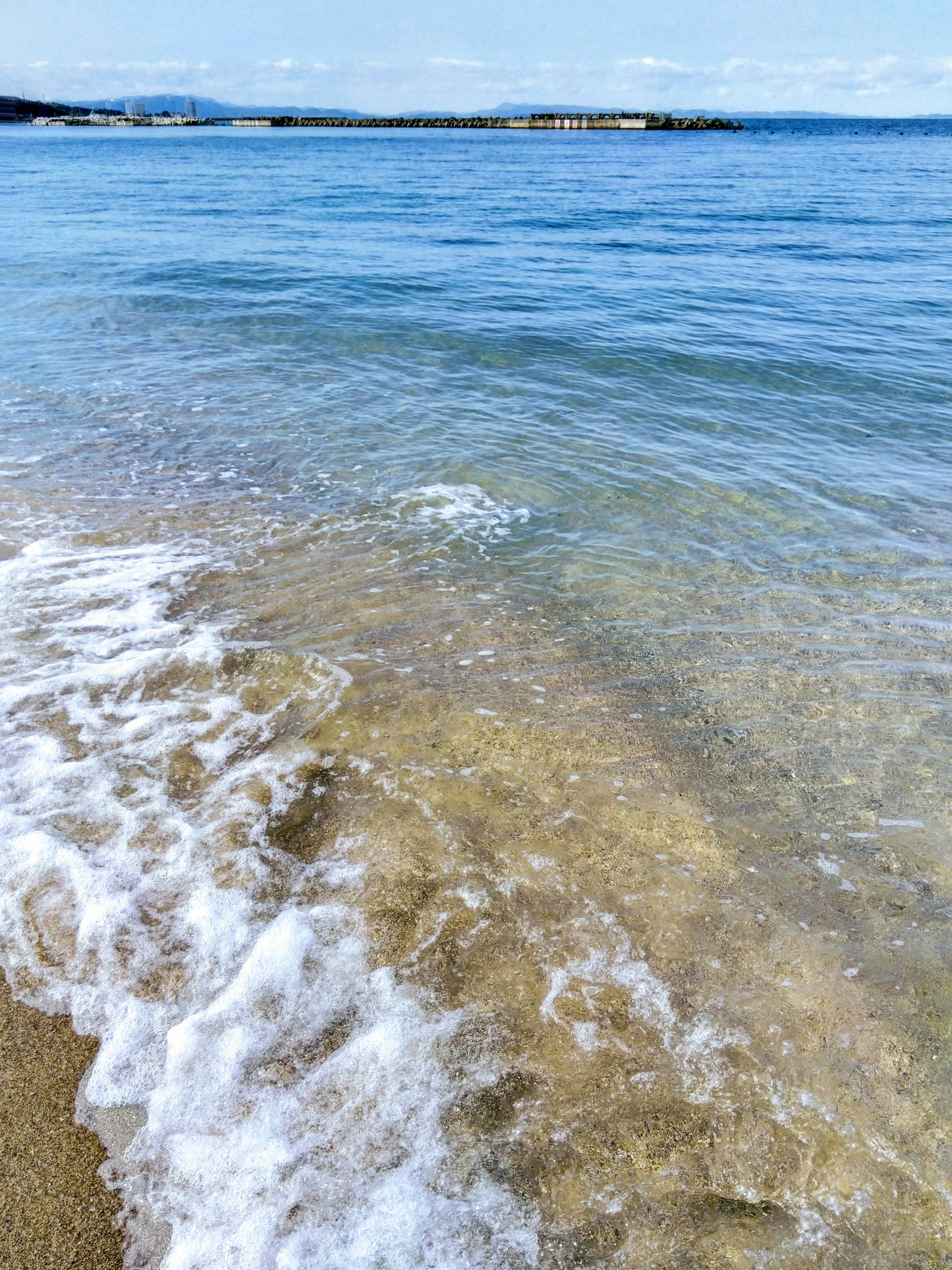 ทะเลสีน้ำเงินสงบที่คลื่นอ่อนโยนซัดเข้าหาชายหาดทราย