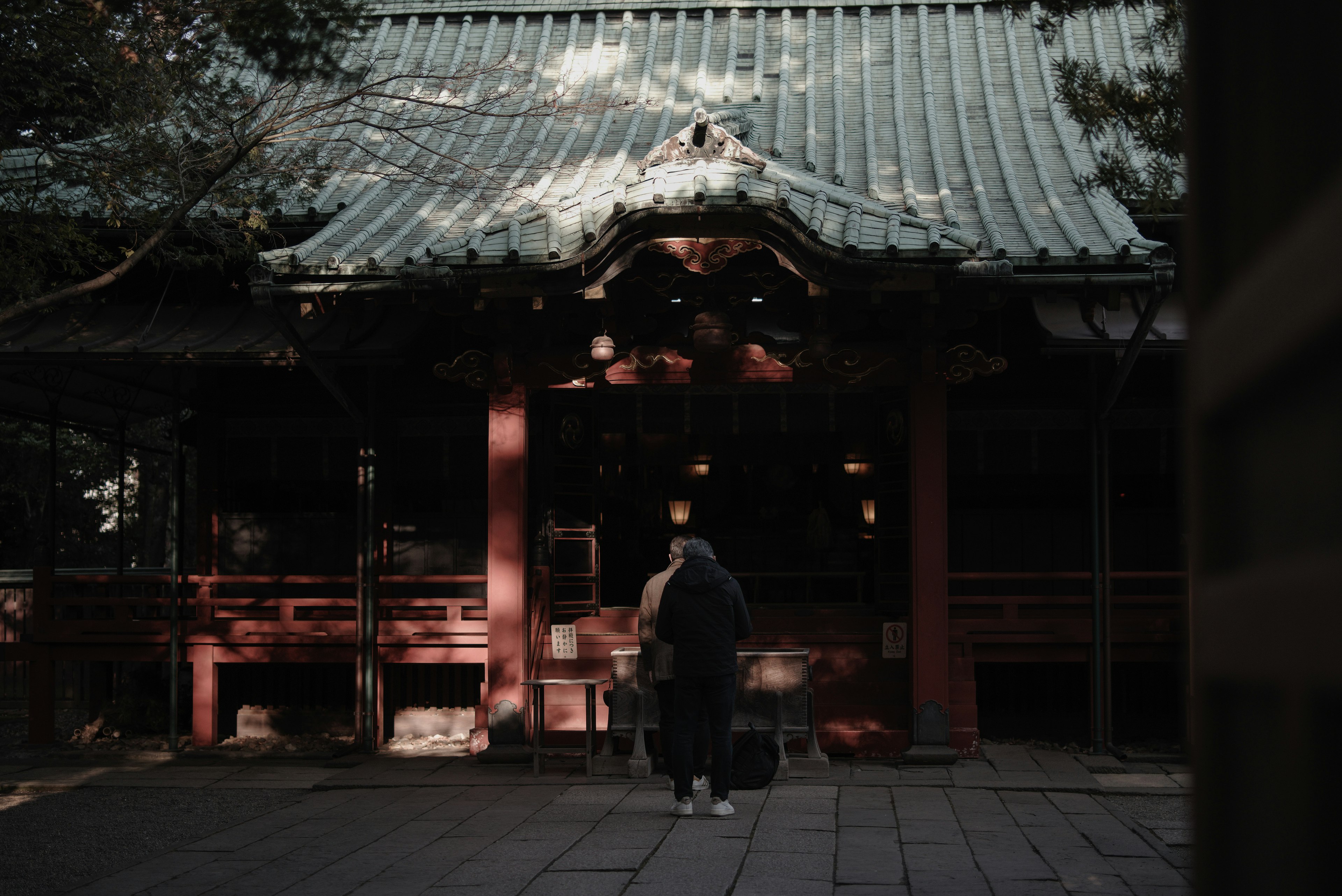 一个人站在一个有红色柱子和传统屋顶的神社前