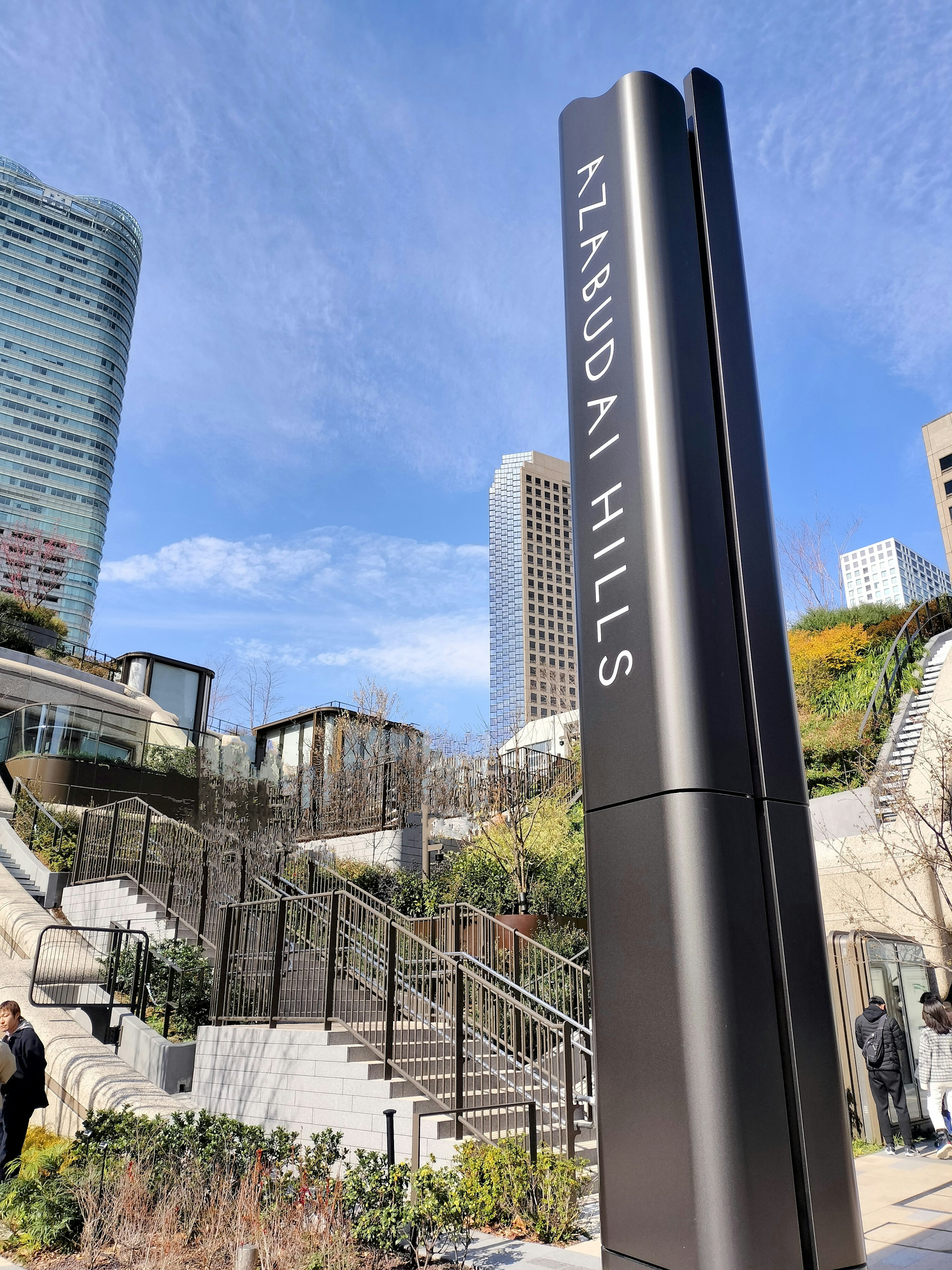 Sign for KAZUO HILLS with skyscrapers in the background