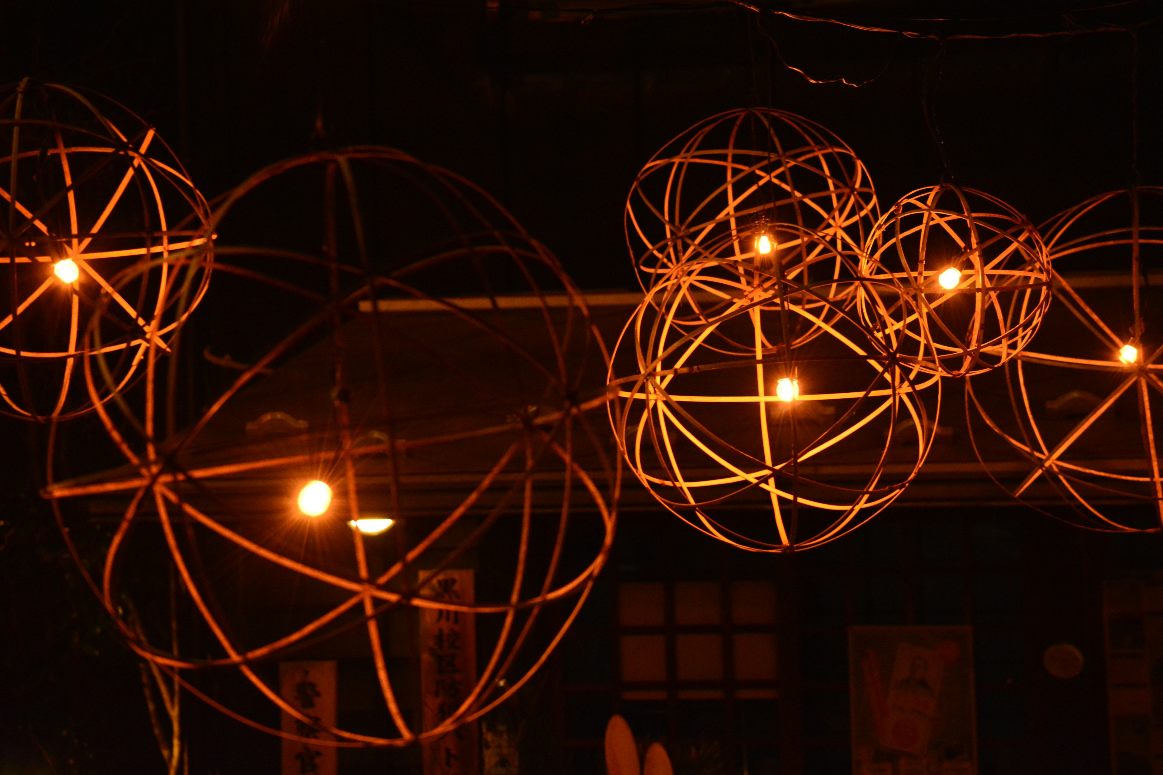 Warm light glowing from bamboo spherical lamps against a dark background