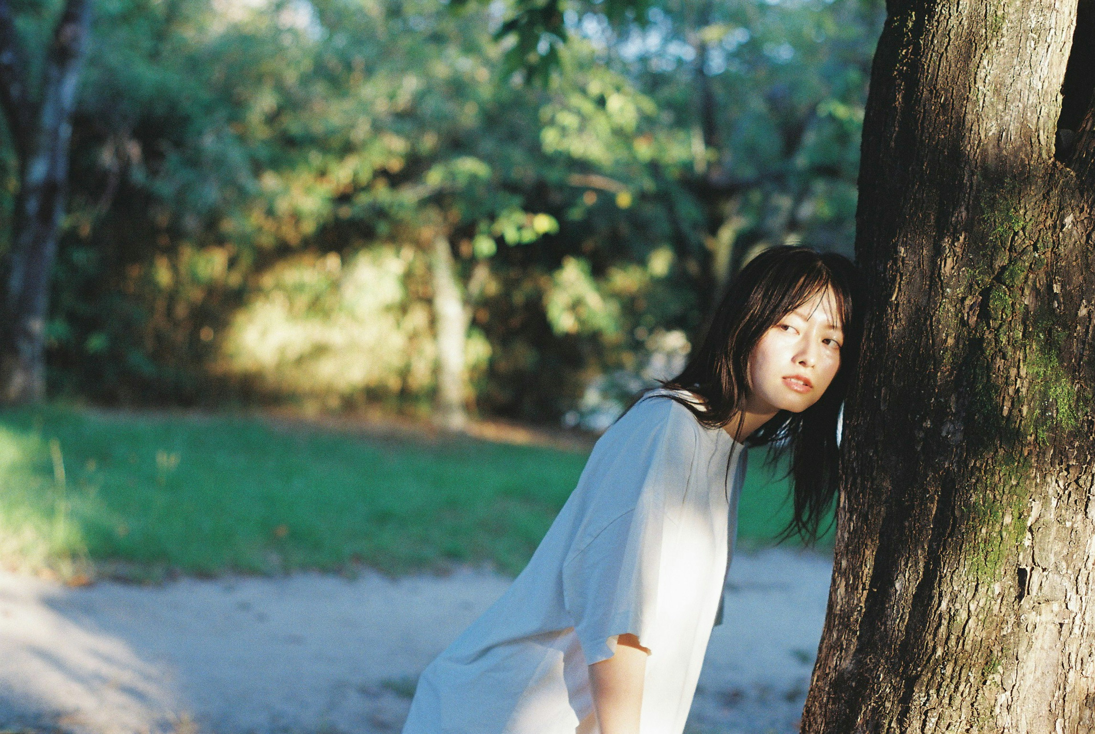 Portrait of a woman leaning against a tree in a forest