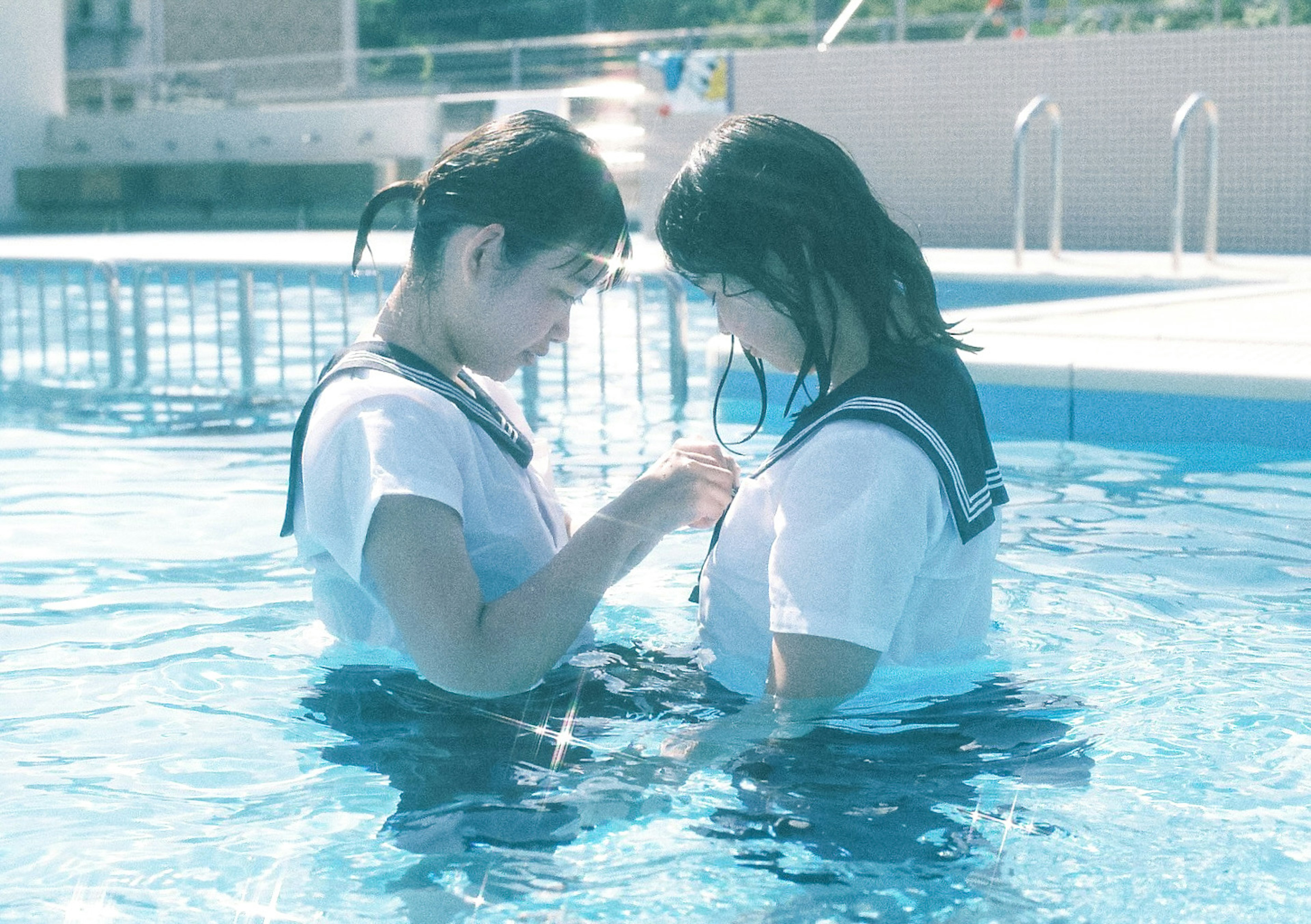 Two girls in swimsuits looking at each other in a swimming pool