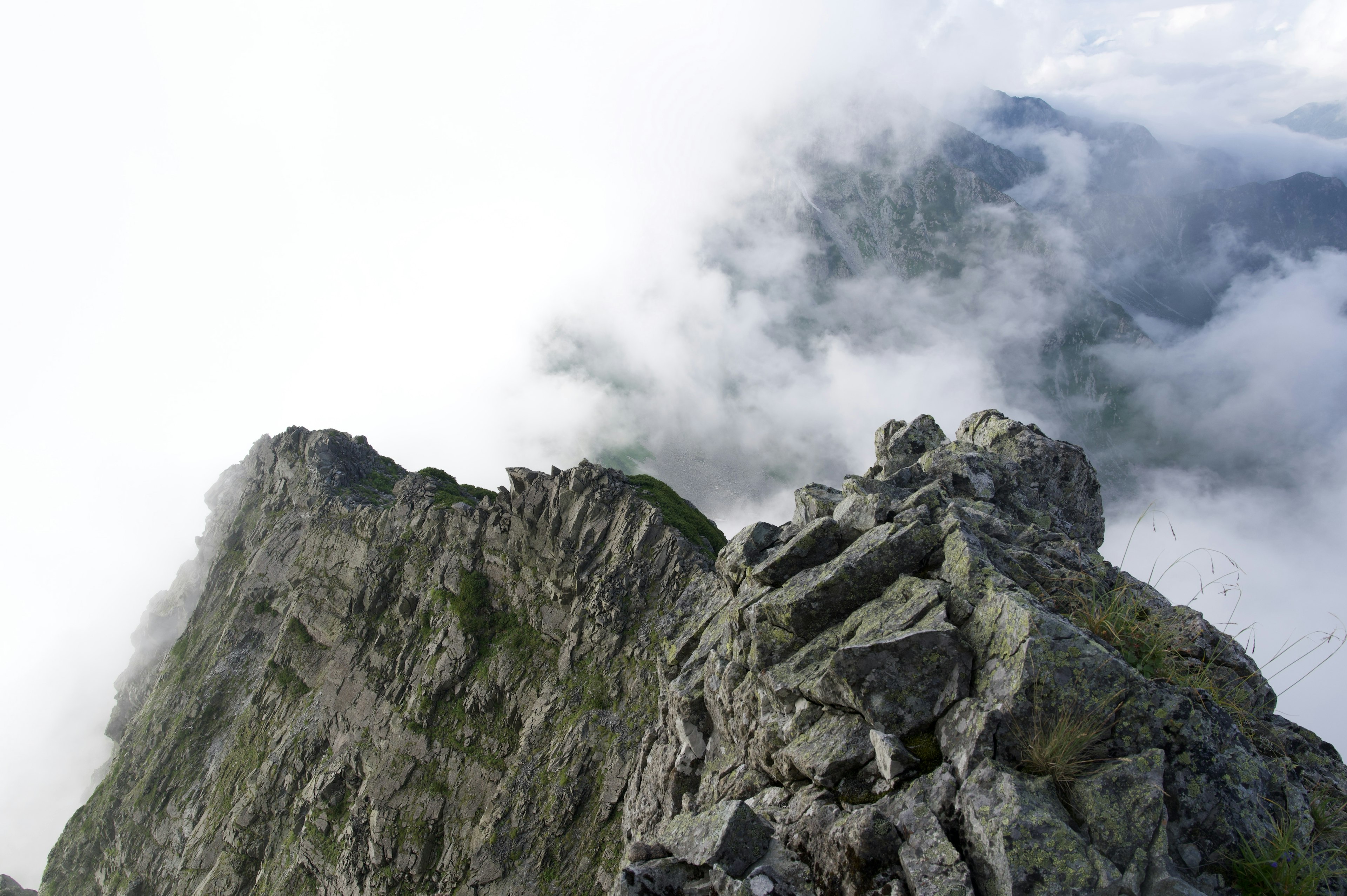 Cima montañosa rocosa envuelta en nubes con un paisaje dramático