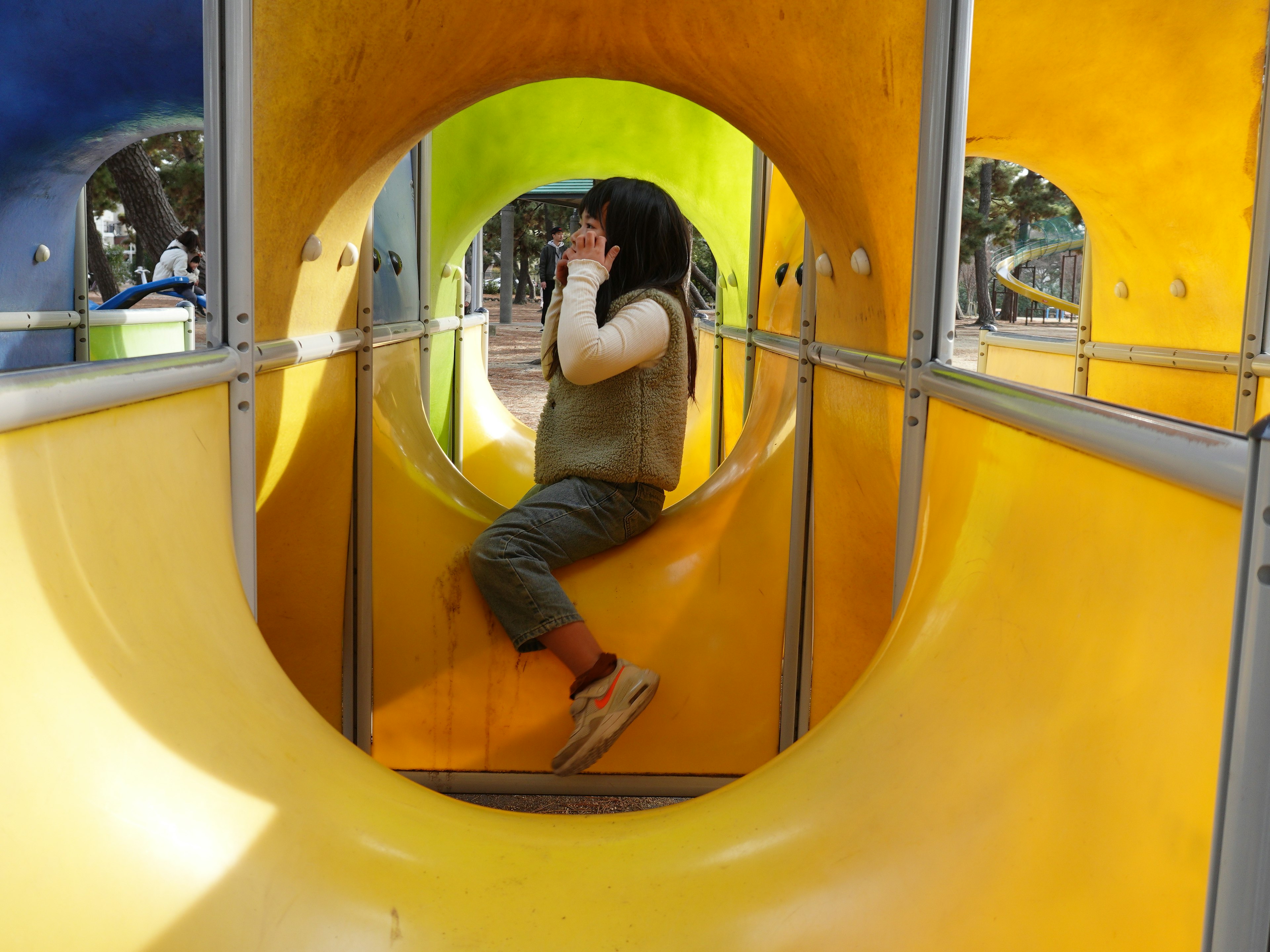 Child playing inside a colorful playground tunnel