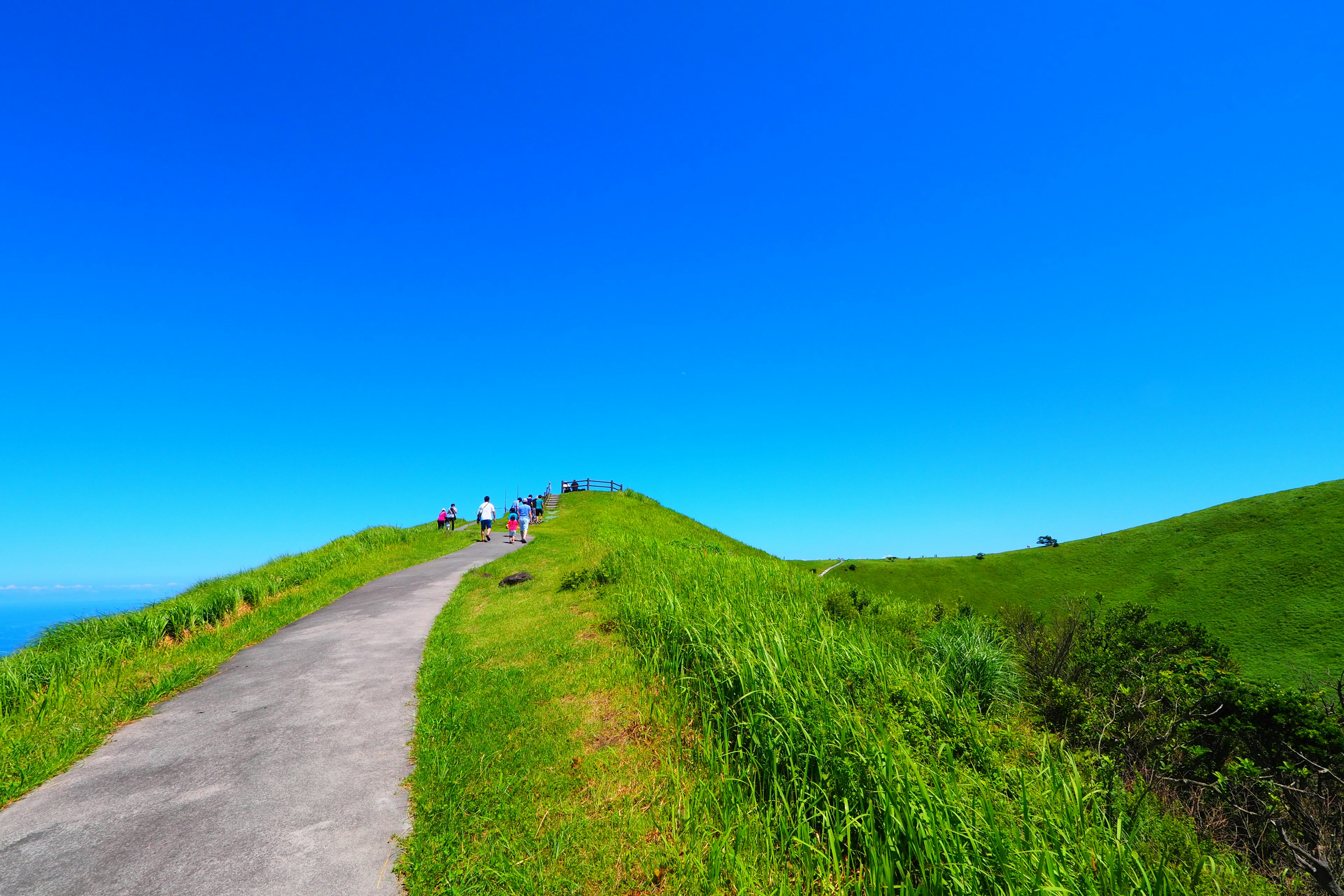 Cielo blu vibrante sopra colline verdi con un sentiero asfaltato