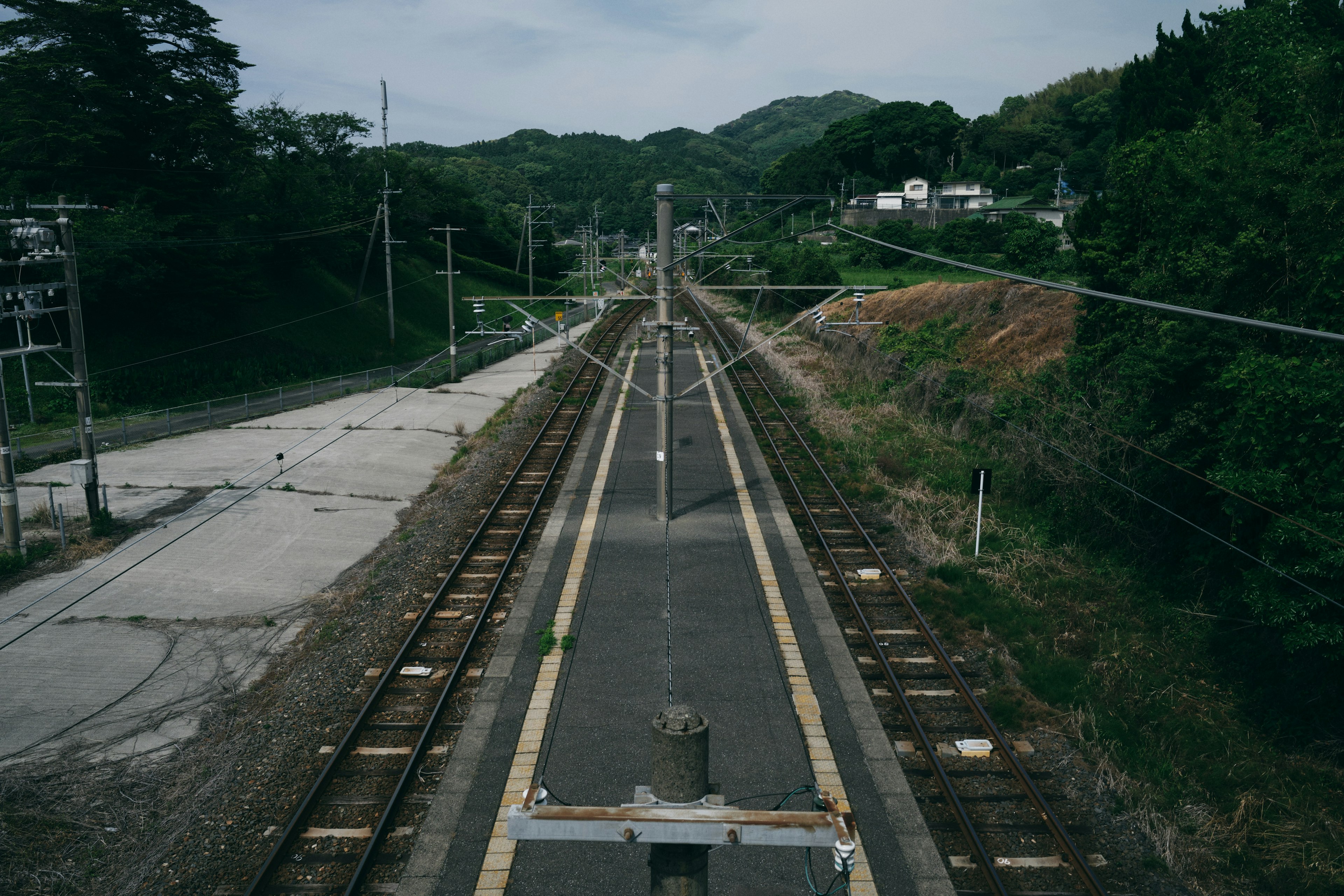 Quiet railway station scene with tracks and green hills