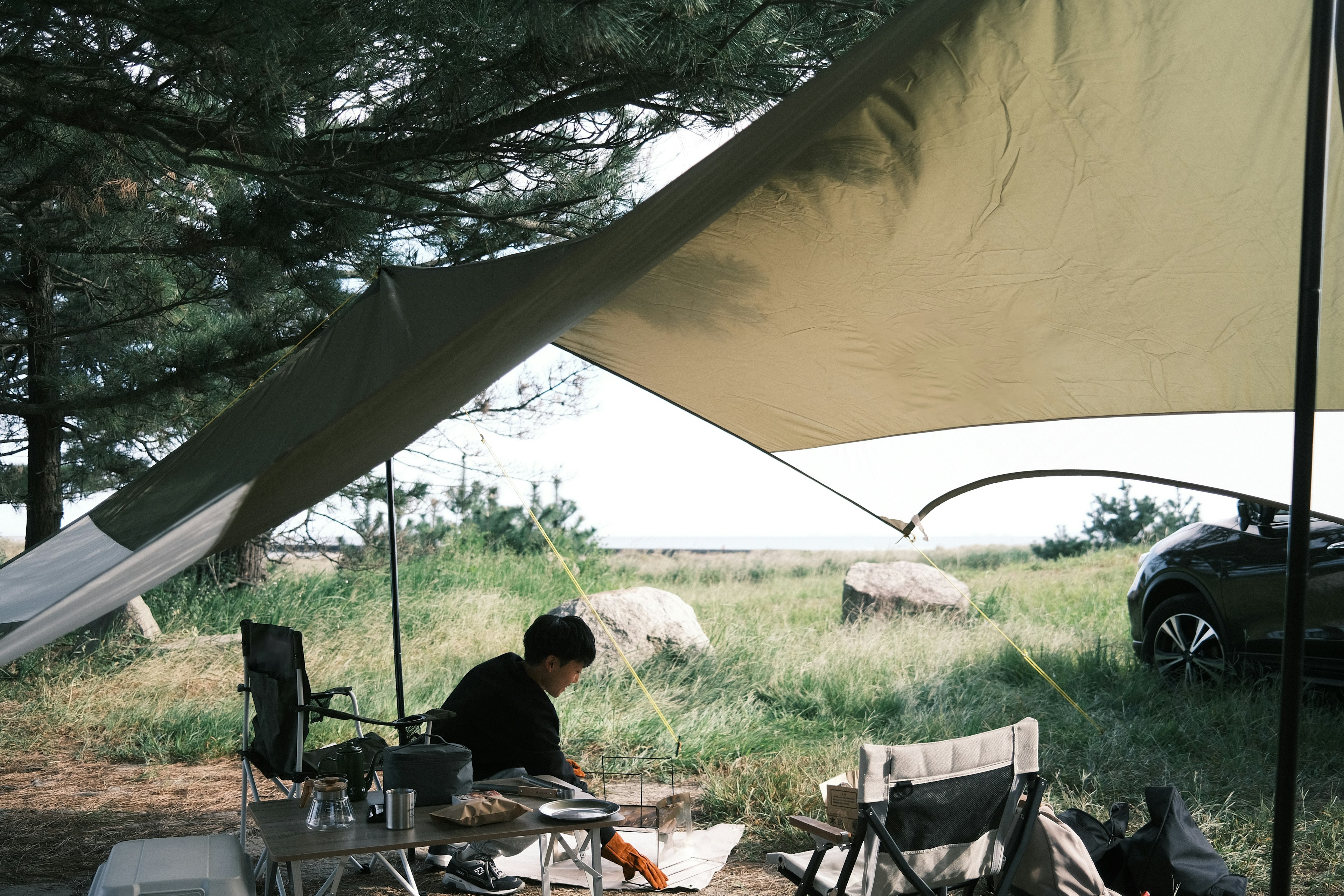 Persona cocinando bajo una tienda en un campamento