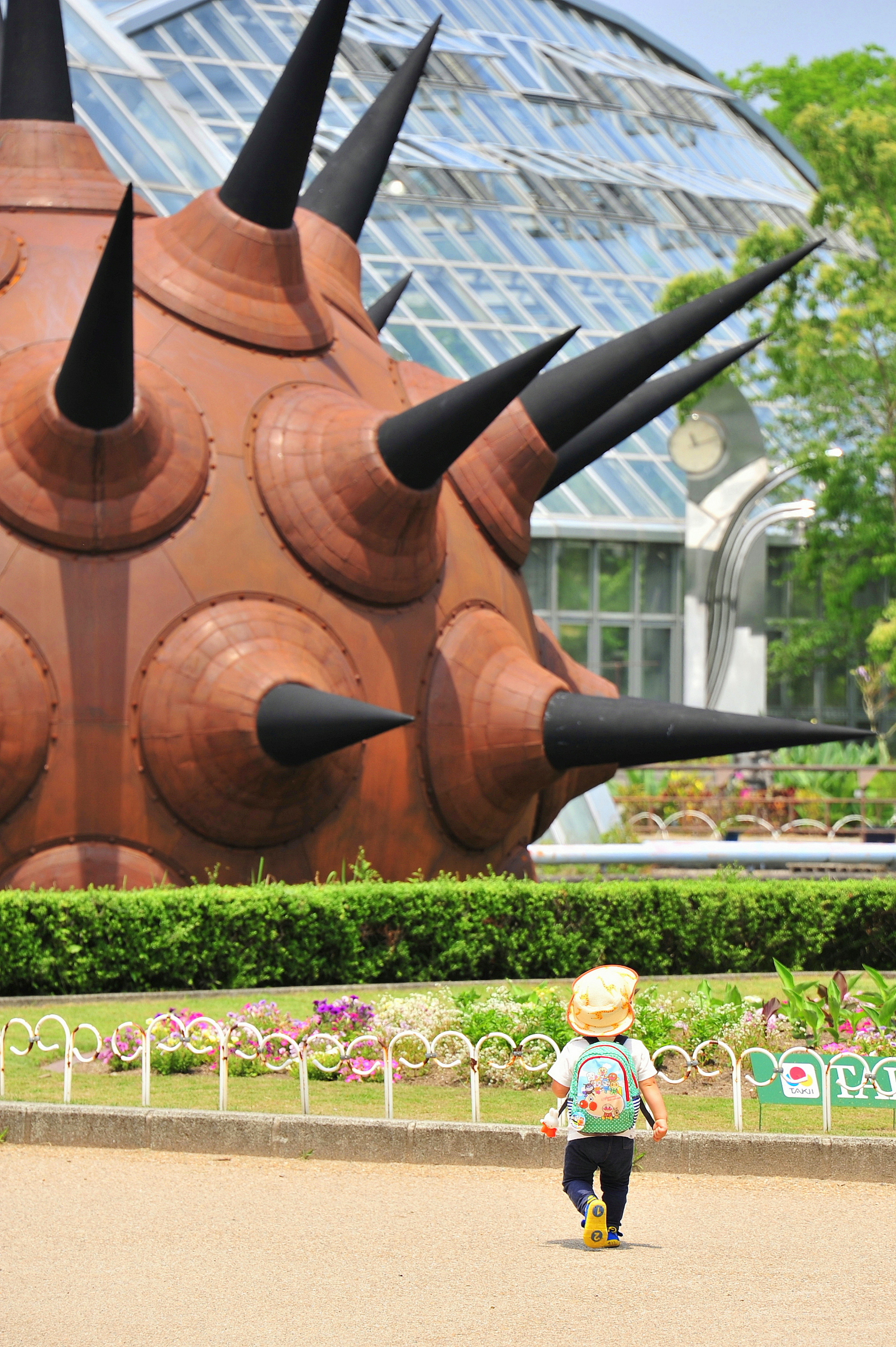 Un bambino che cammina davanti a una grande scultura spigolosa in un parco