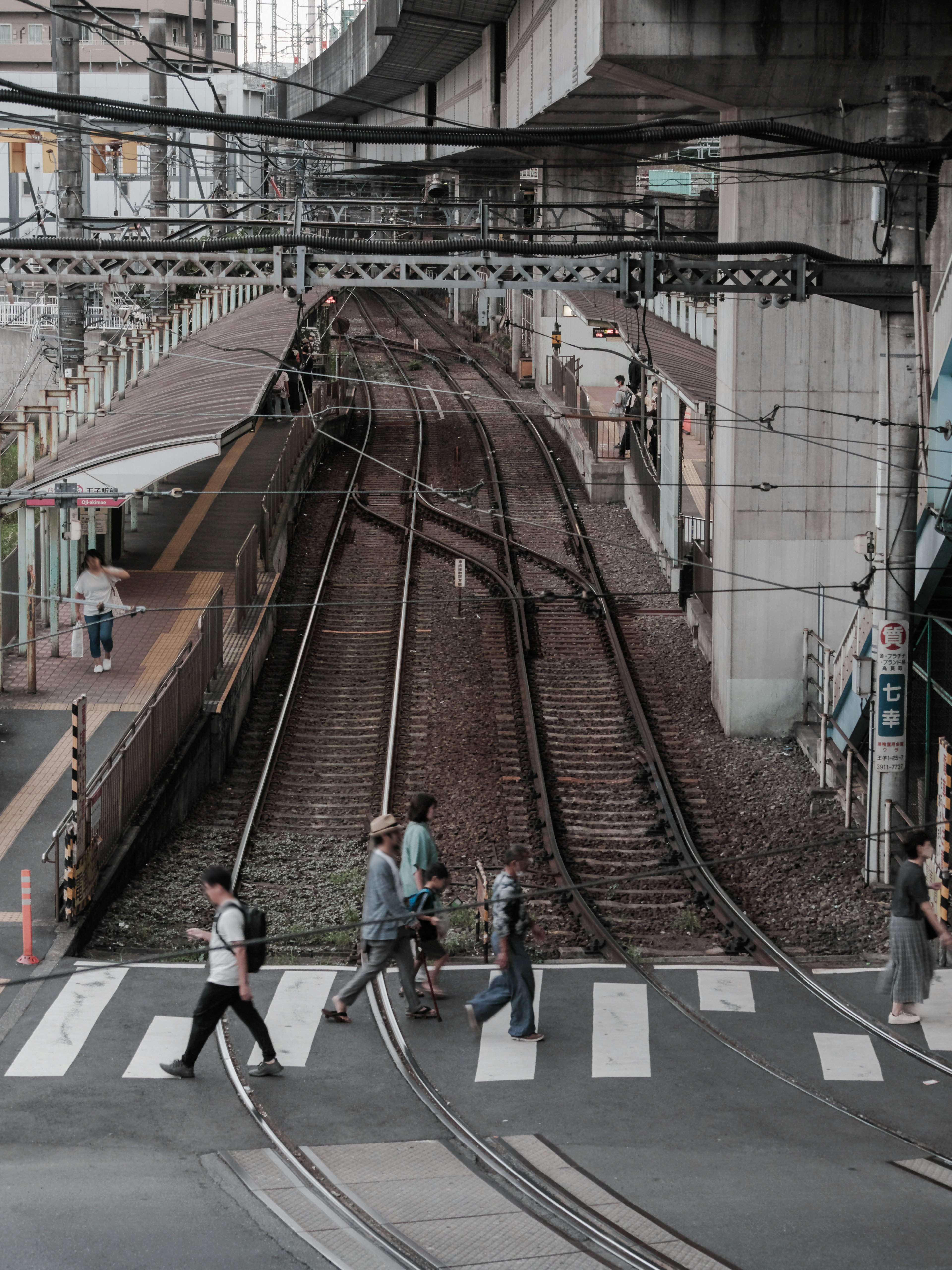 街の交差点で歩行者が線路を渡っている風景