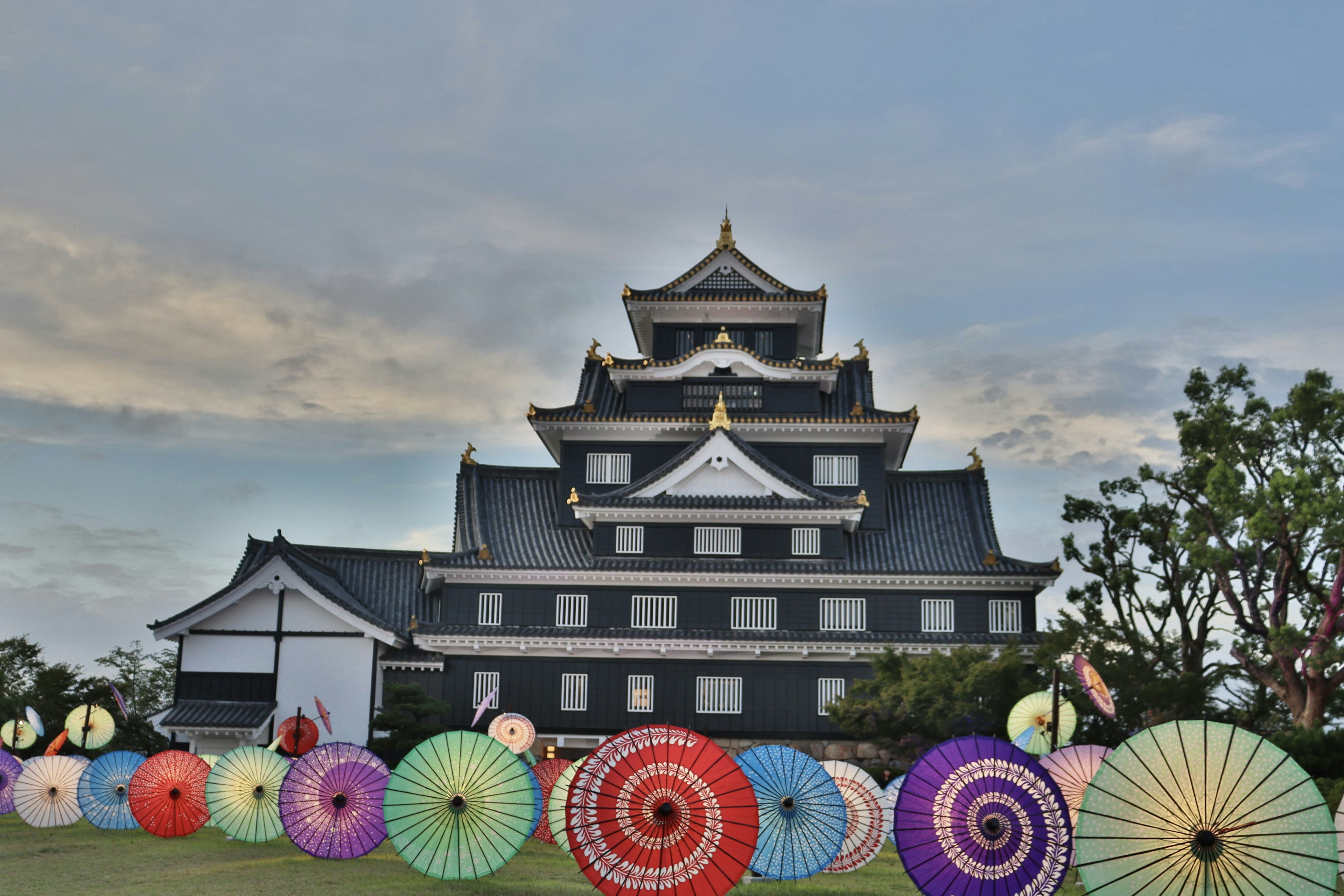 Black castle with colorful Japanese umbrellas in the foreground