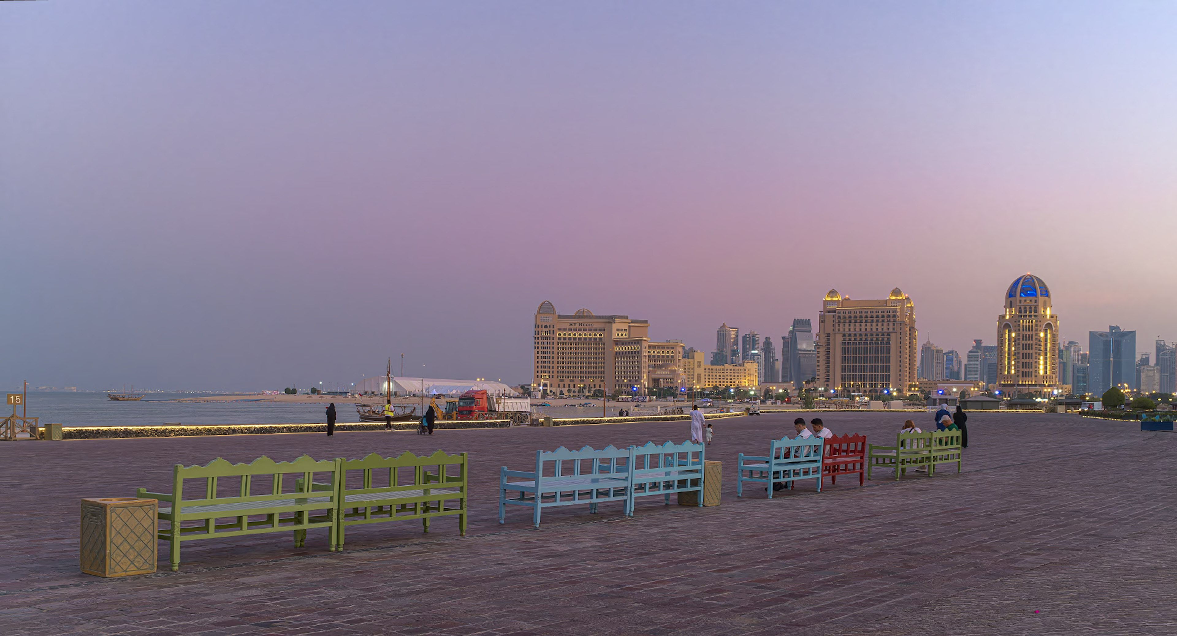 Colorful benches along the Qatar coastline with a sunset backdrop