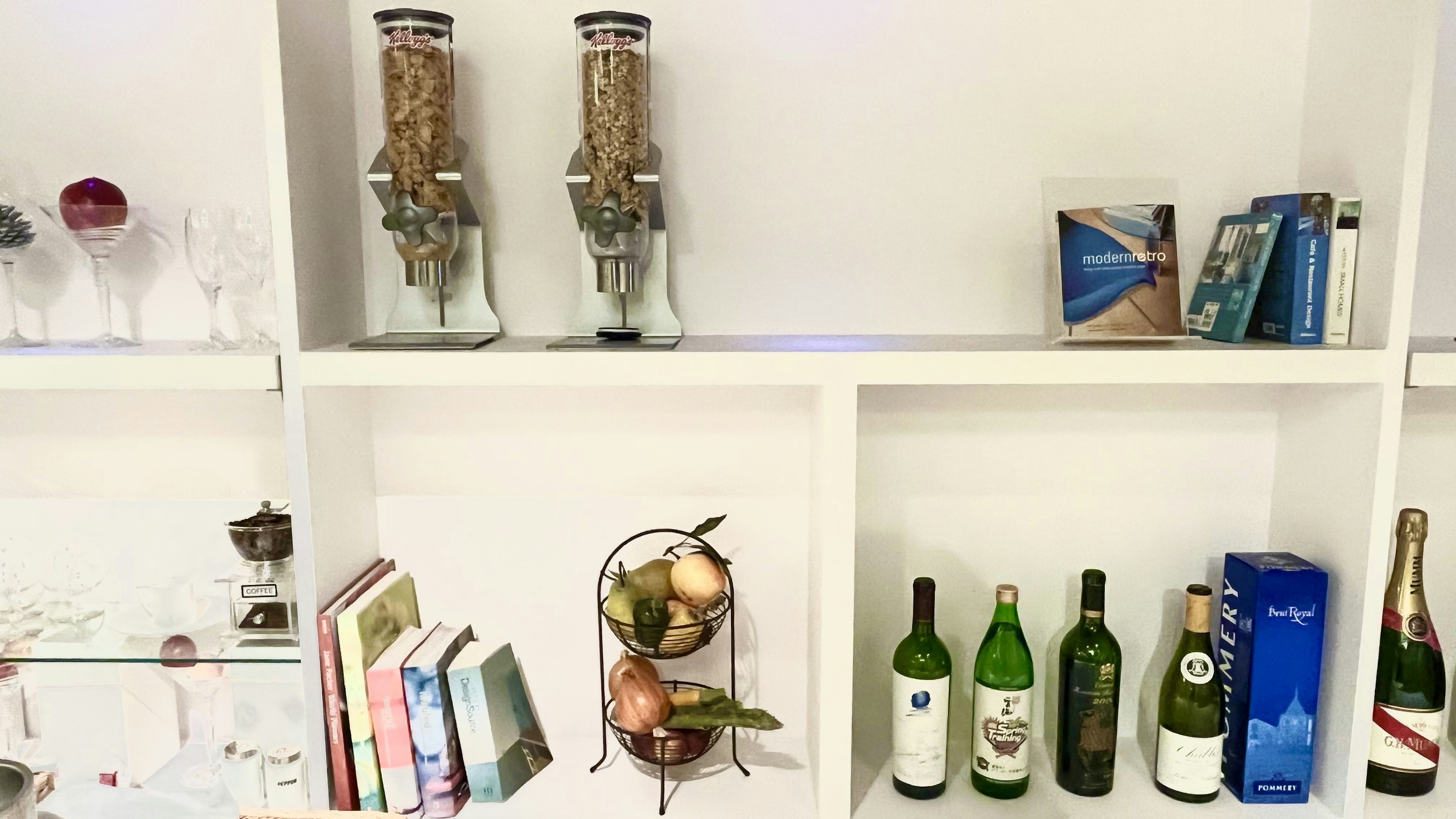 White shelves displaying glasses books and wine bottles