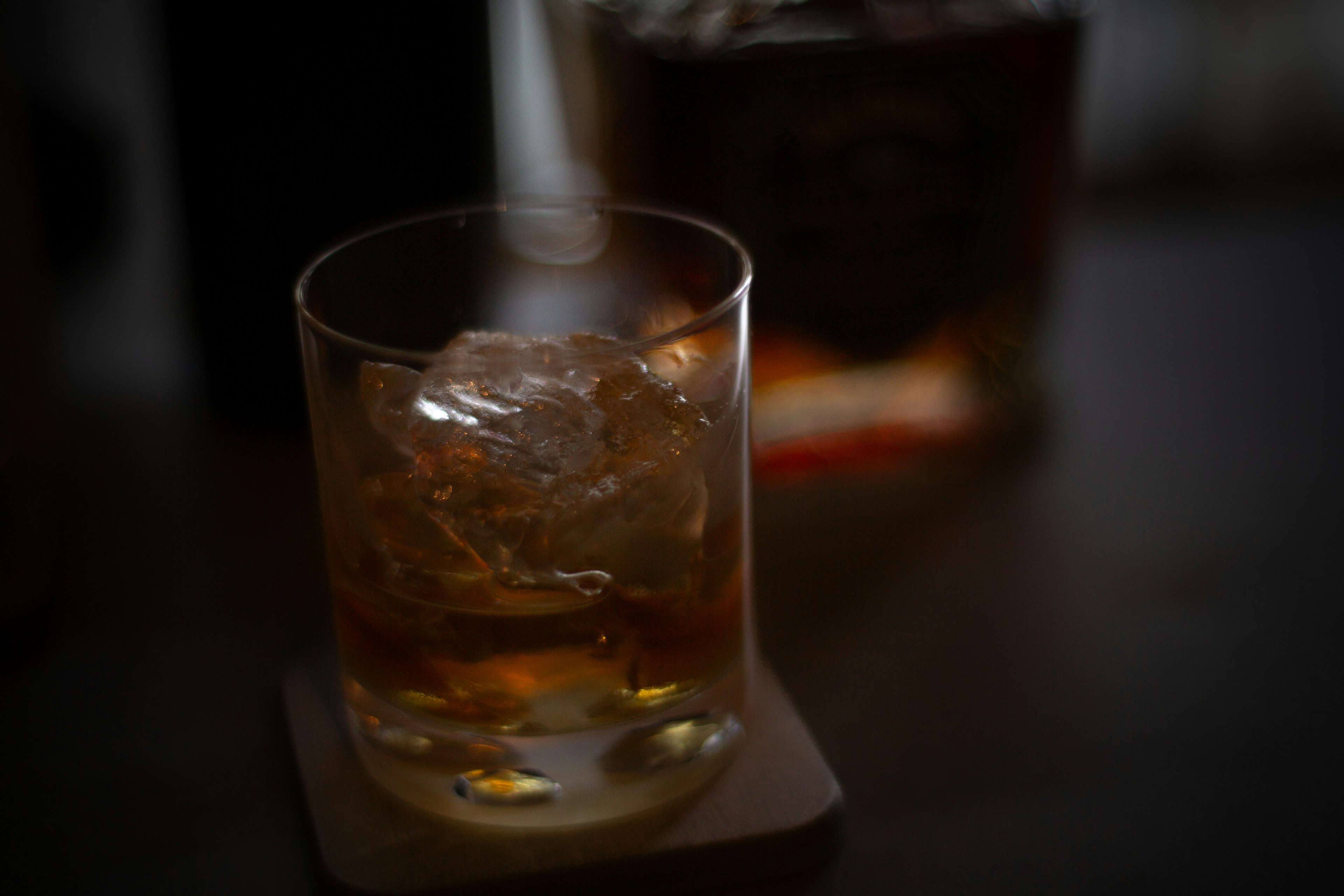 Whiskey glass filled with ice and a blurred bottle in the background