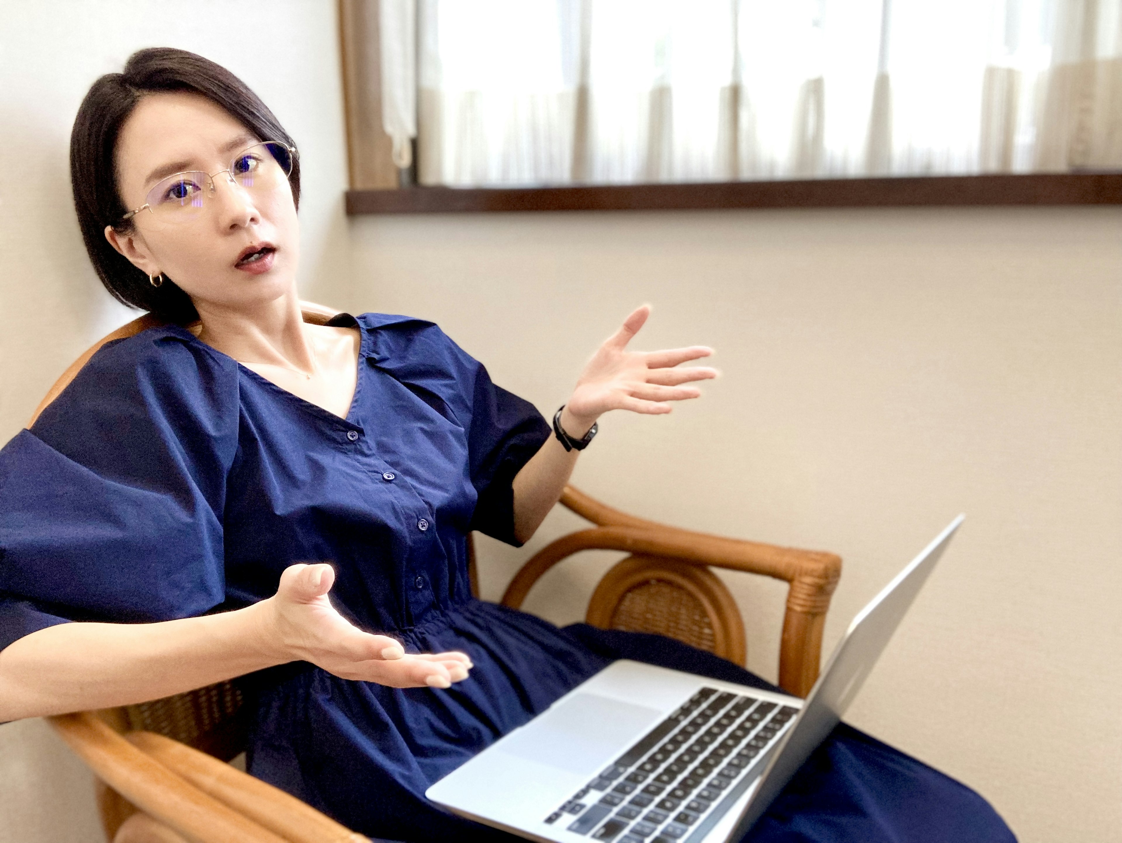 A woman sitting in a chair using a laptop with a surprised expression