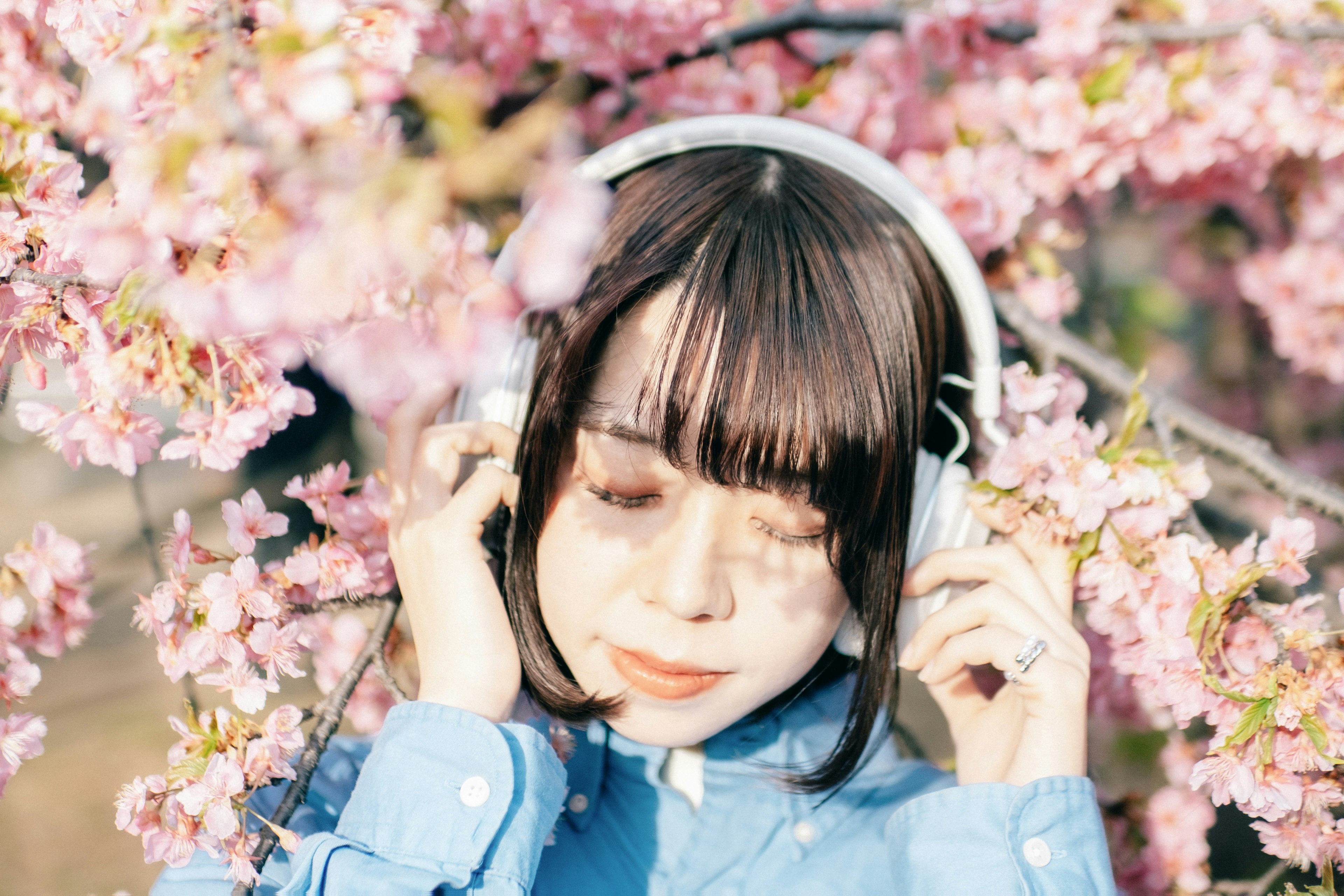 Une femme portant des écouteurs profitant de la musique entourée de cerisiers en fleurs