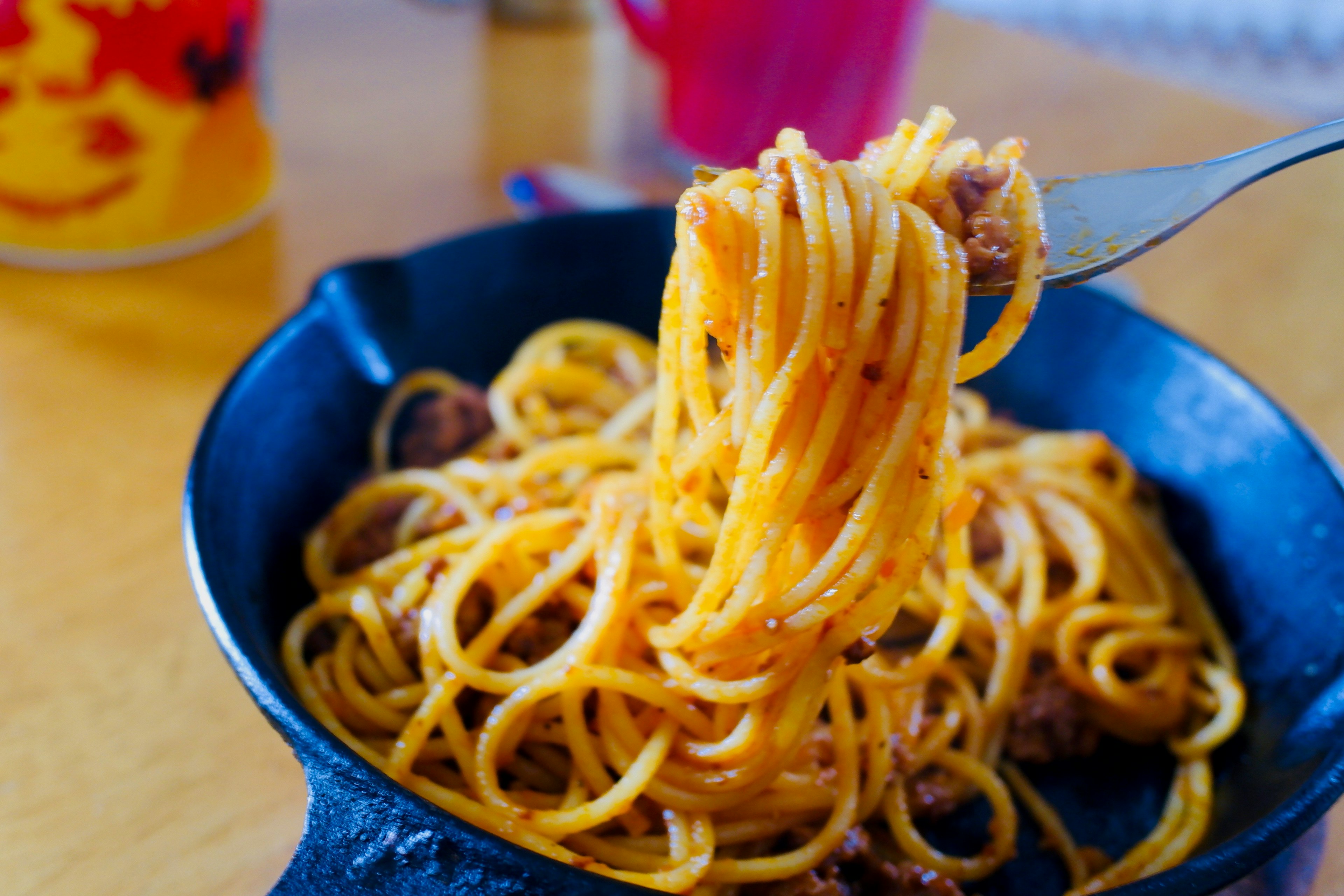 スキレットに盛られたスパゲッティの盛り付けとフォークでつかまれた麺