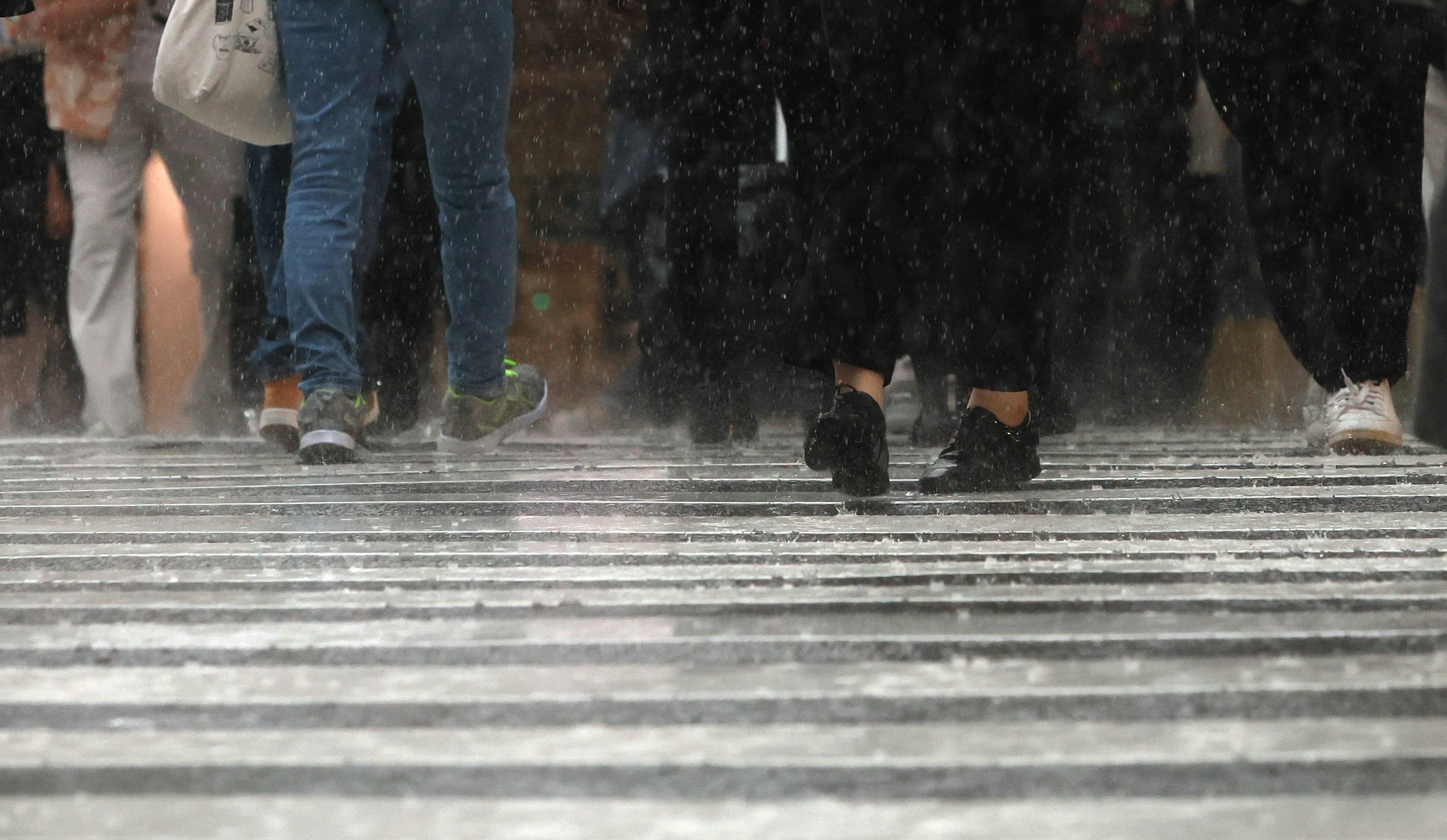 Pieds de piétons traversant une rue sous la pluie