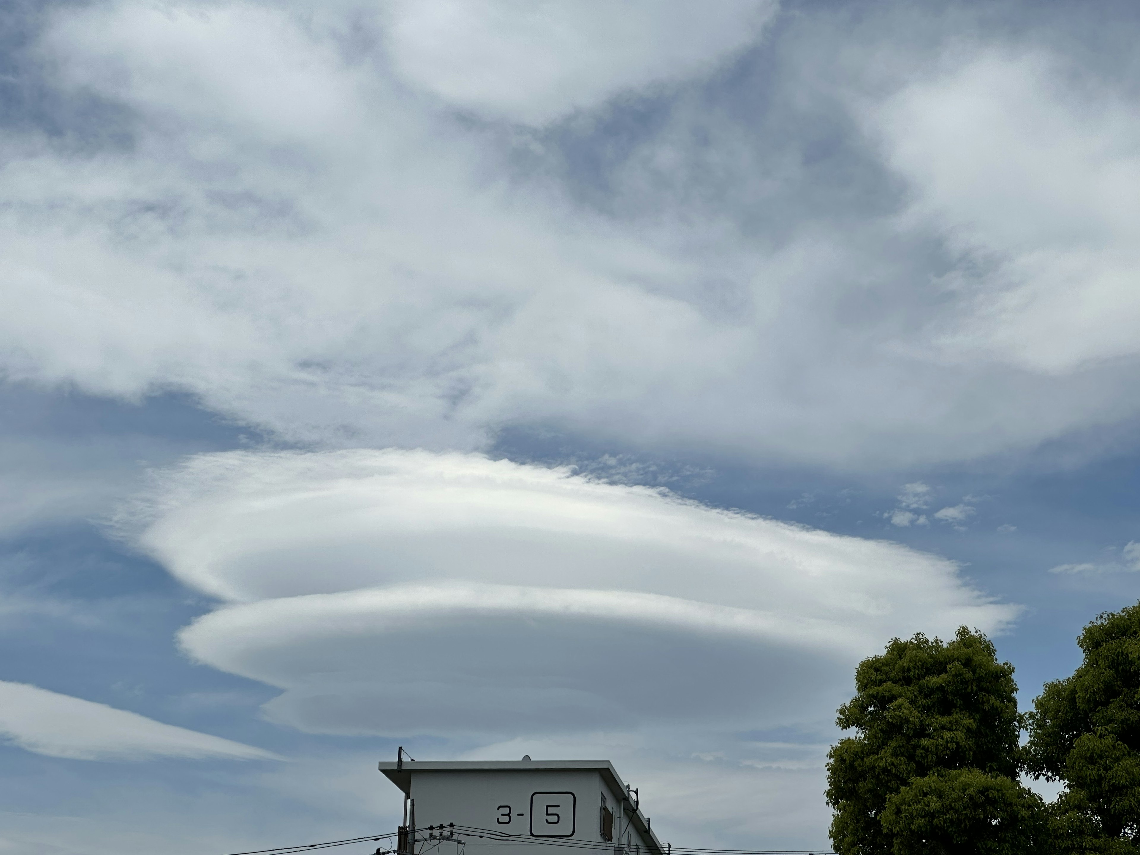 Nuvole lenticolari sopra un edificio con cielo blu chiaro