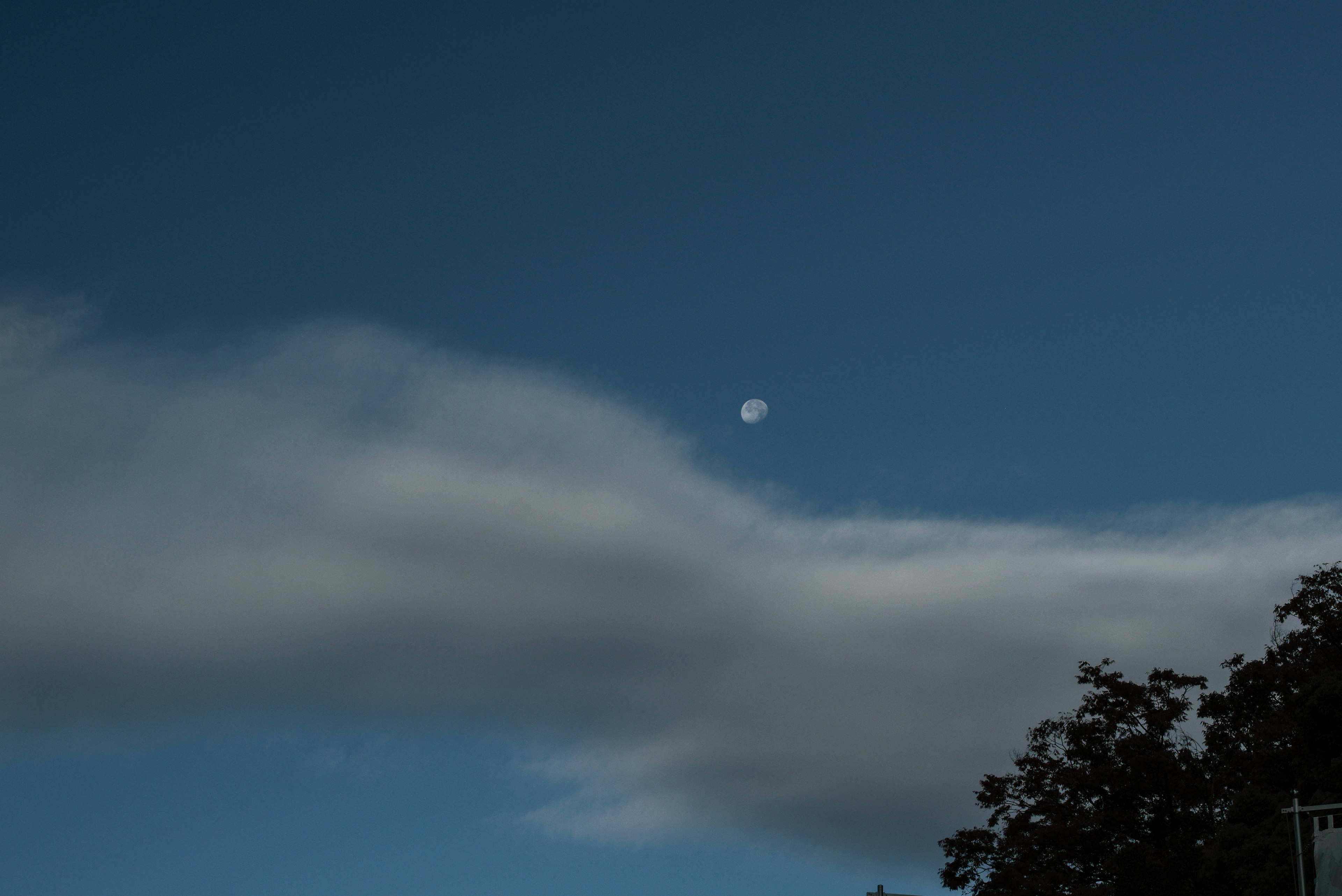 Vista della luna che spunta tra le nuvole in un cielo blu