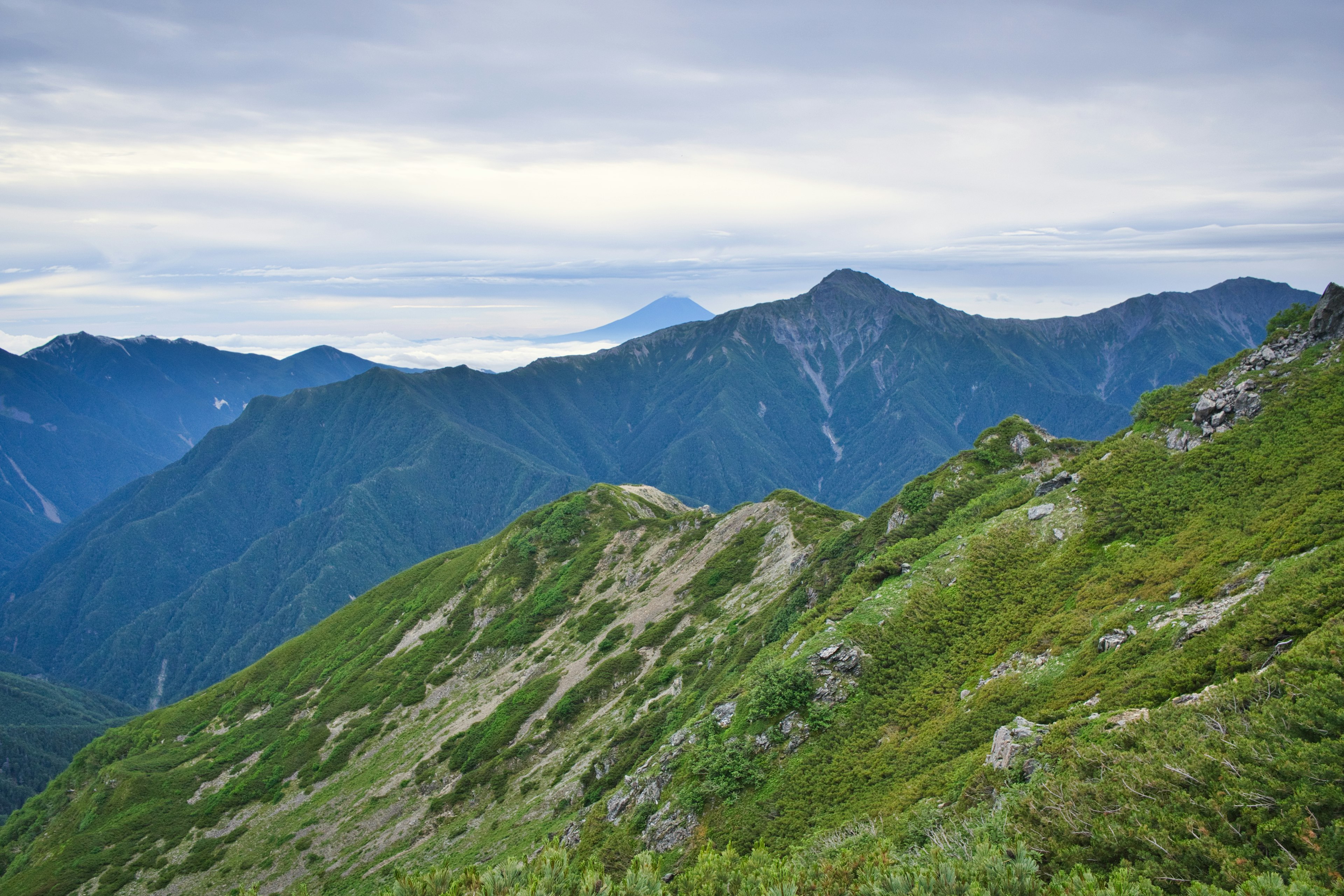 雲霧繚繞的天空下的綠色山坡和遠處的山峰