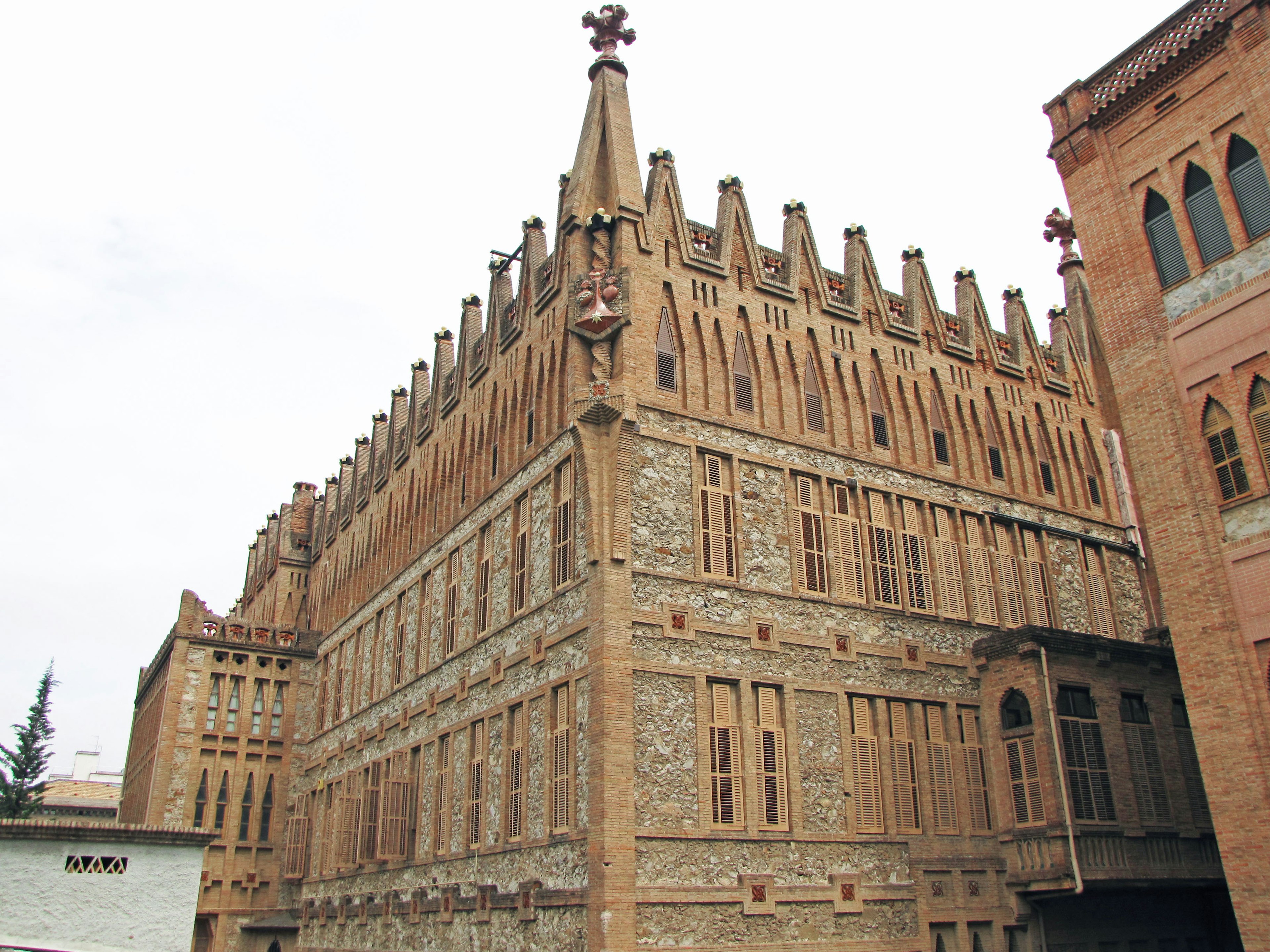 Historic building exterior made of reddish stone featuring pointed towers and decorative elements