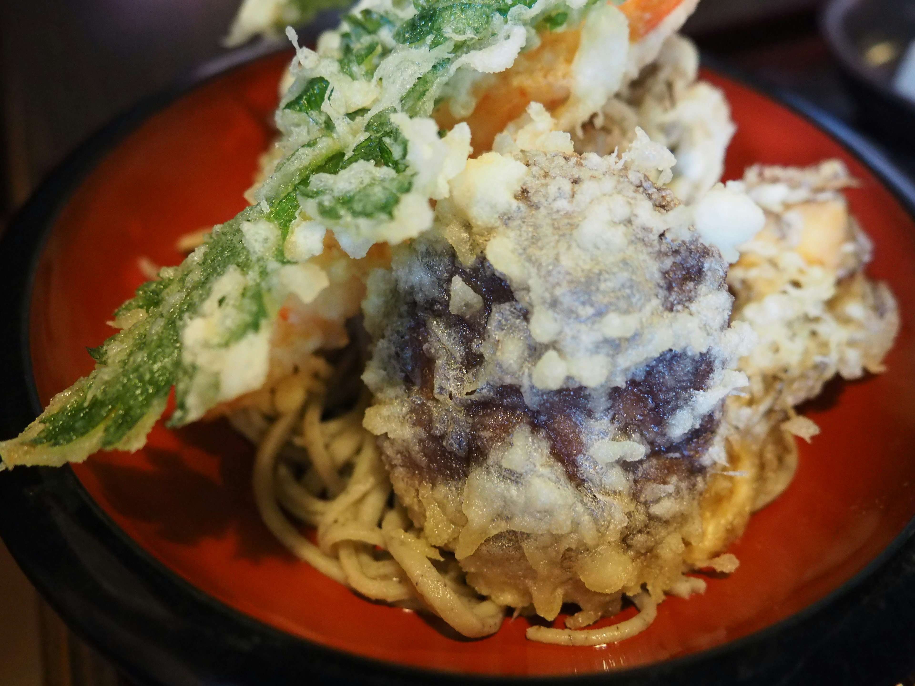 Un plato delicioso de soba tempura servido en un plato rojo