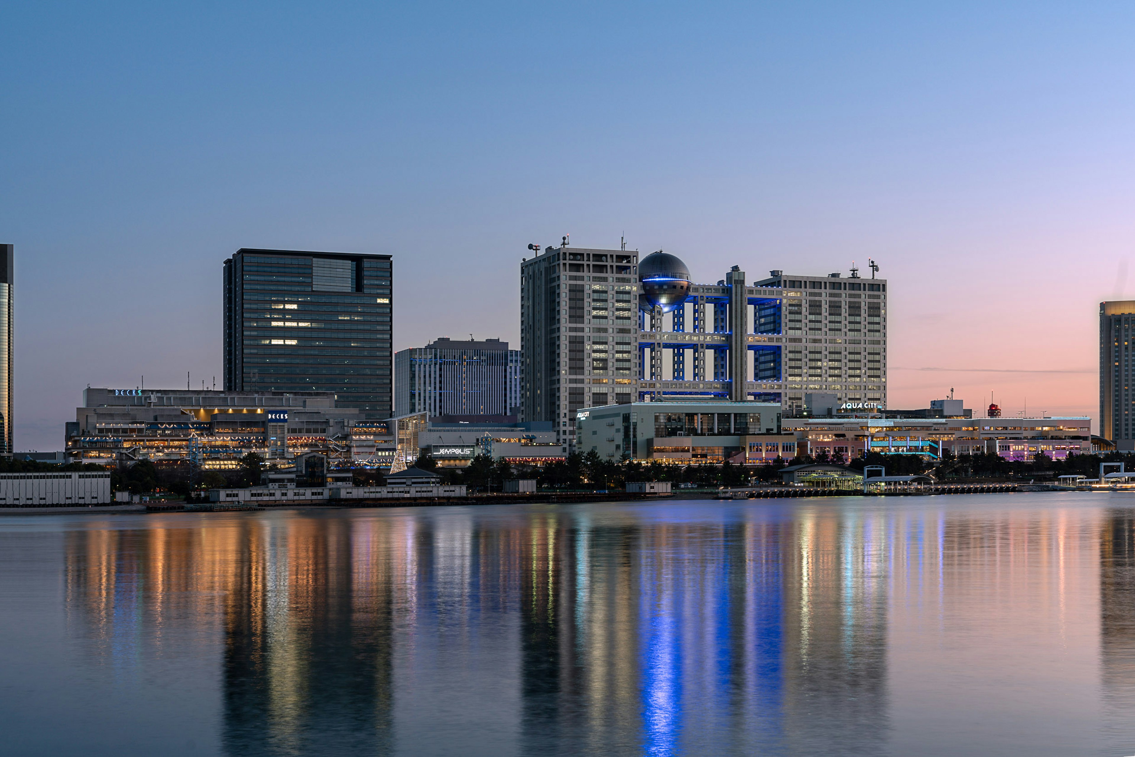 City skyline reflecting on water at dusk with modern buildings