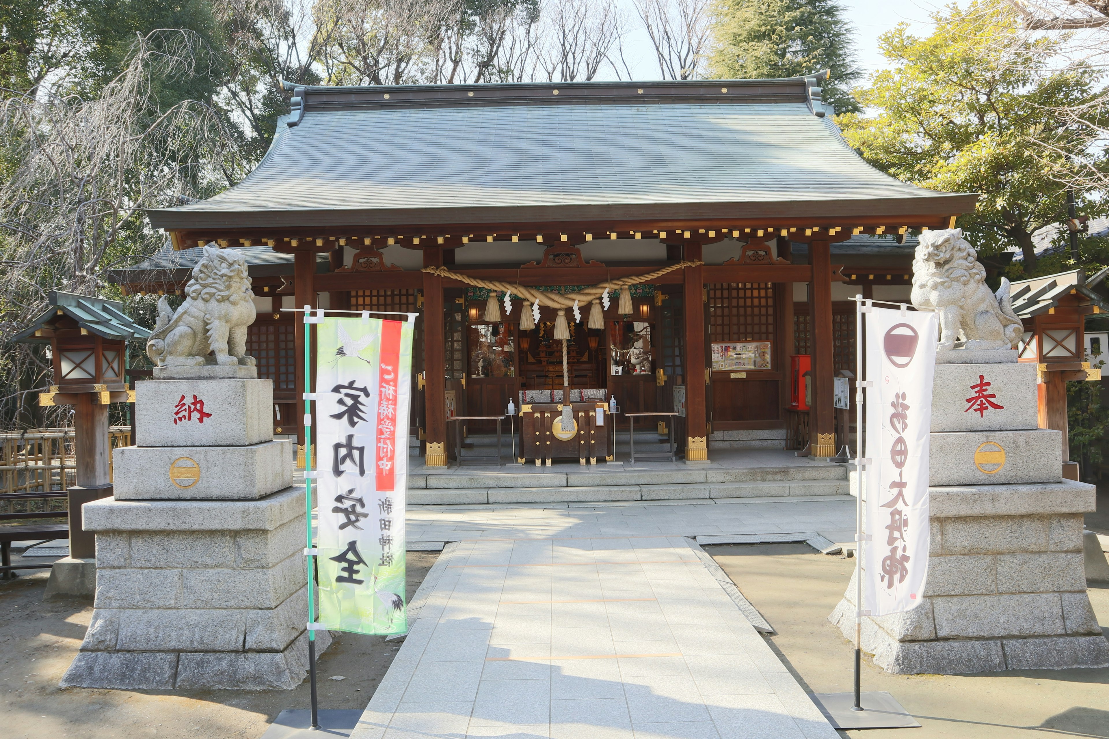 Entrance of a shrine with stone guardian dogs and decorative banners