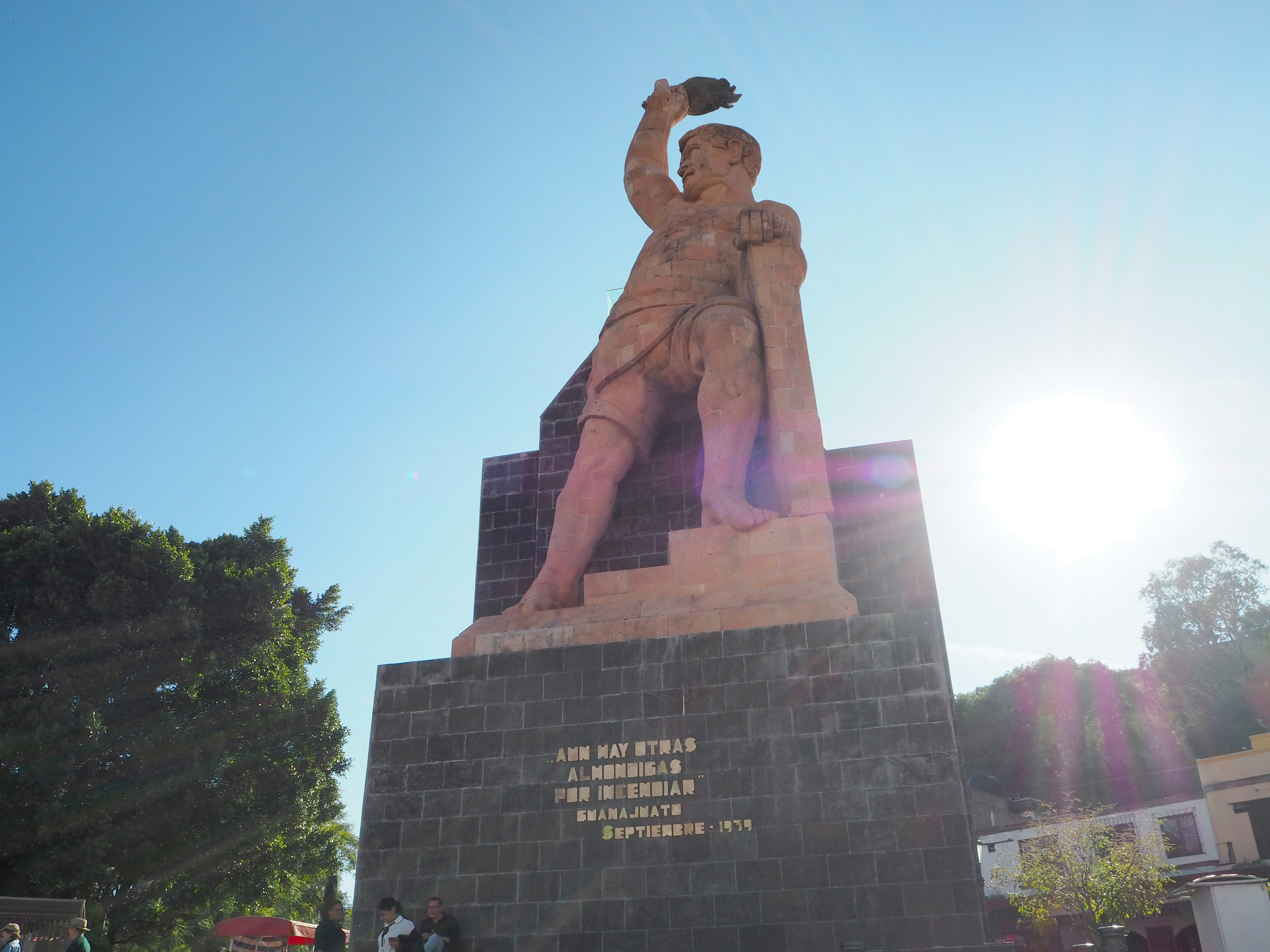 Grande statua che si erge sotto un cielo blu con sole splendente