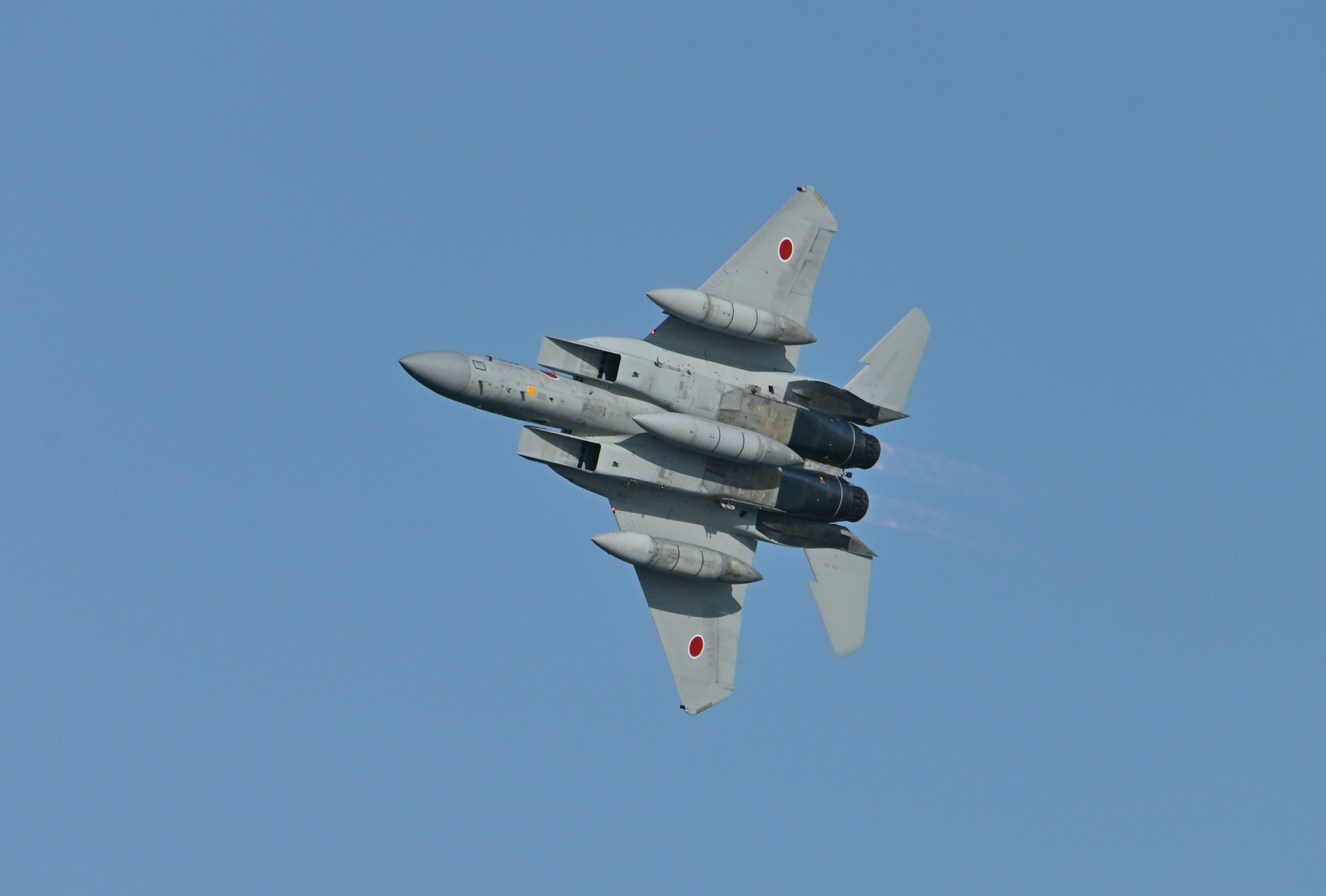 Top view of a fighter jet in flight against a blue sky