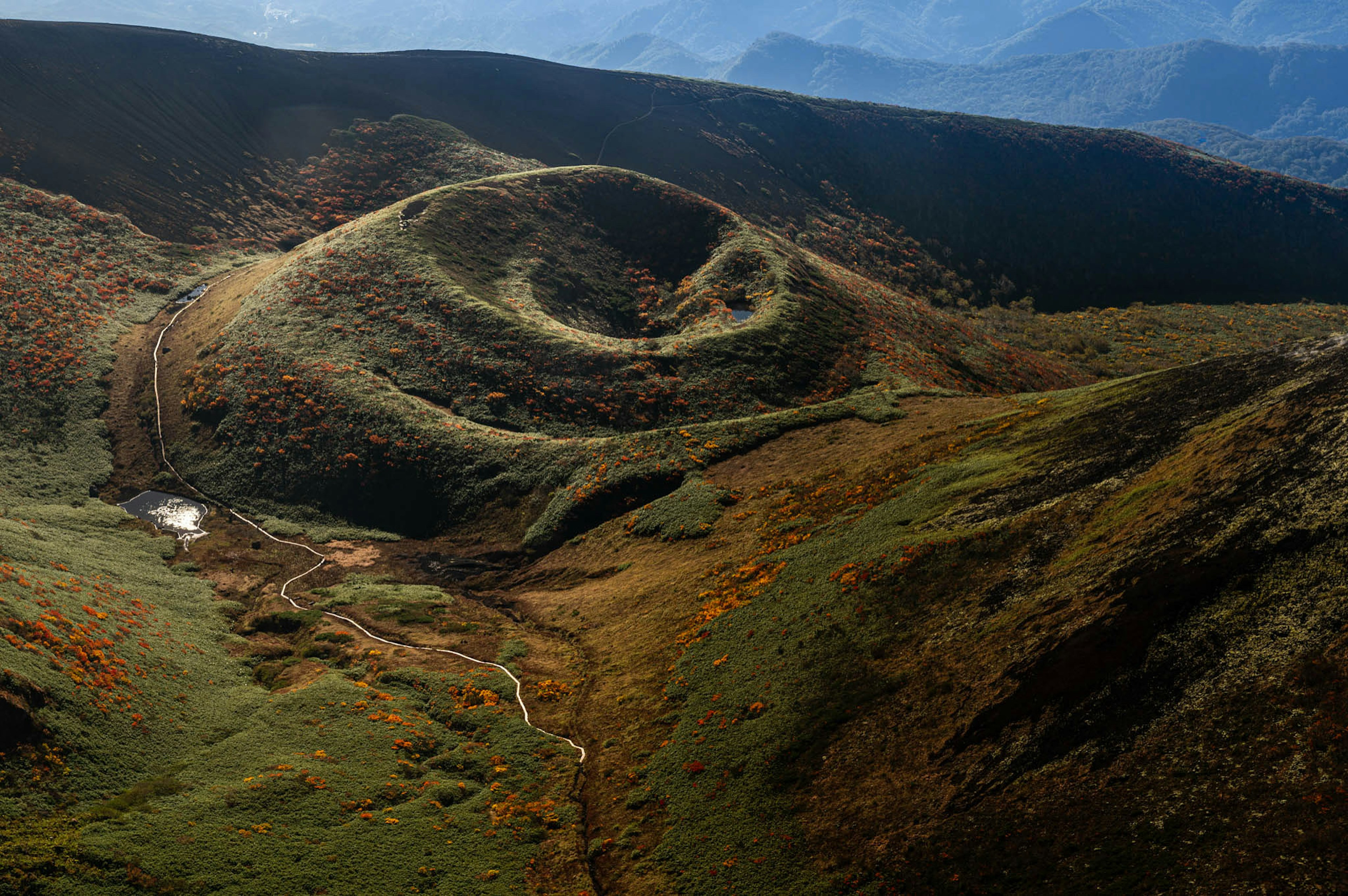 Vue pittoresque de collines vertes avec des chemins sinueux et un feuillage coloré