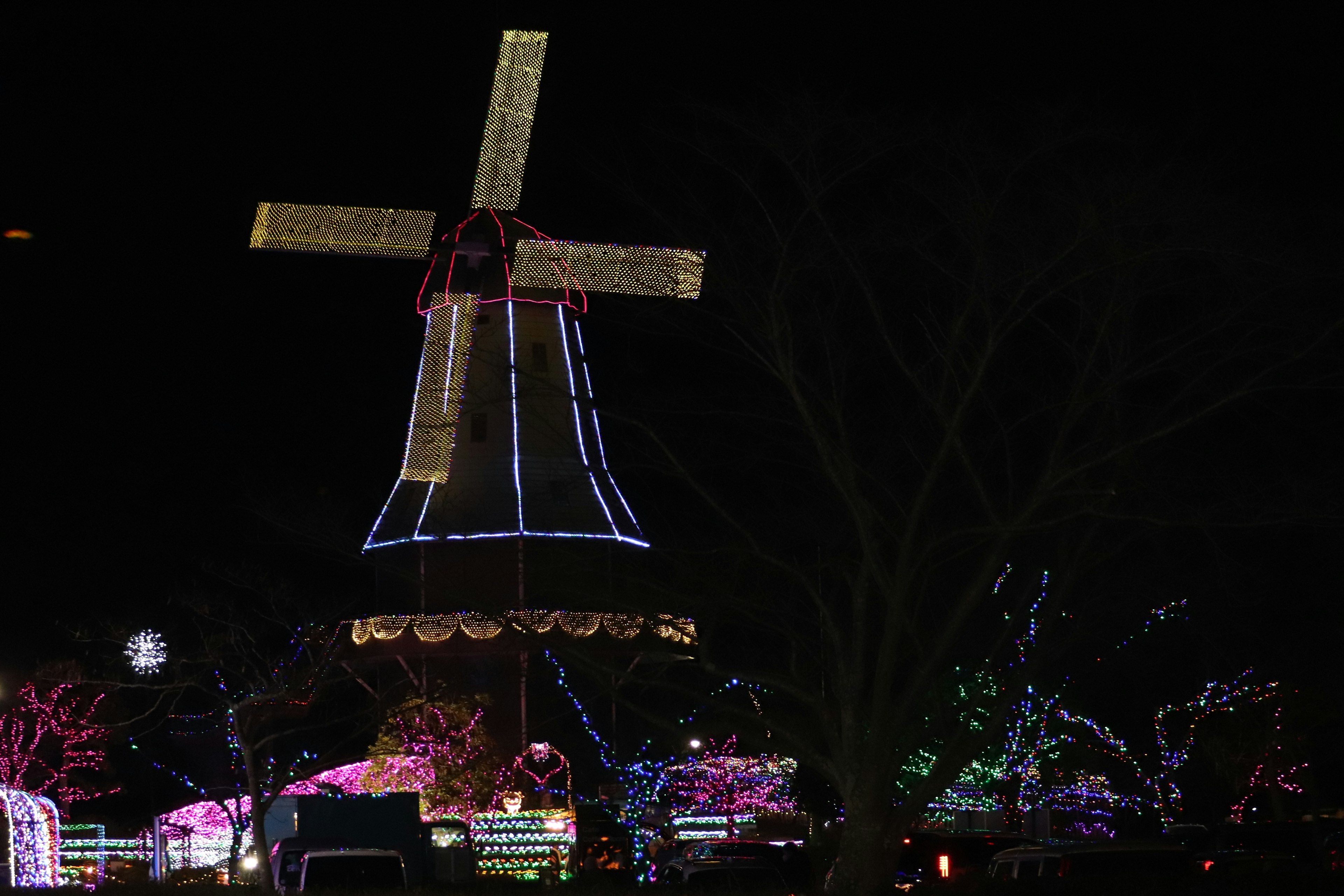 Moulin illuminé la nuit avec des lumières colorées sur les arbres environnants