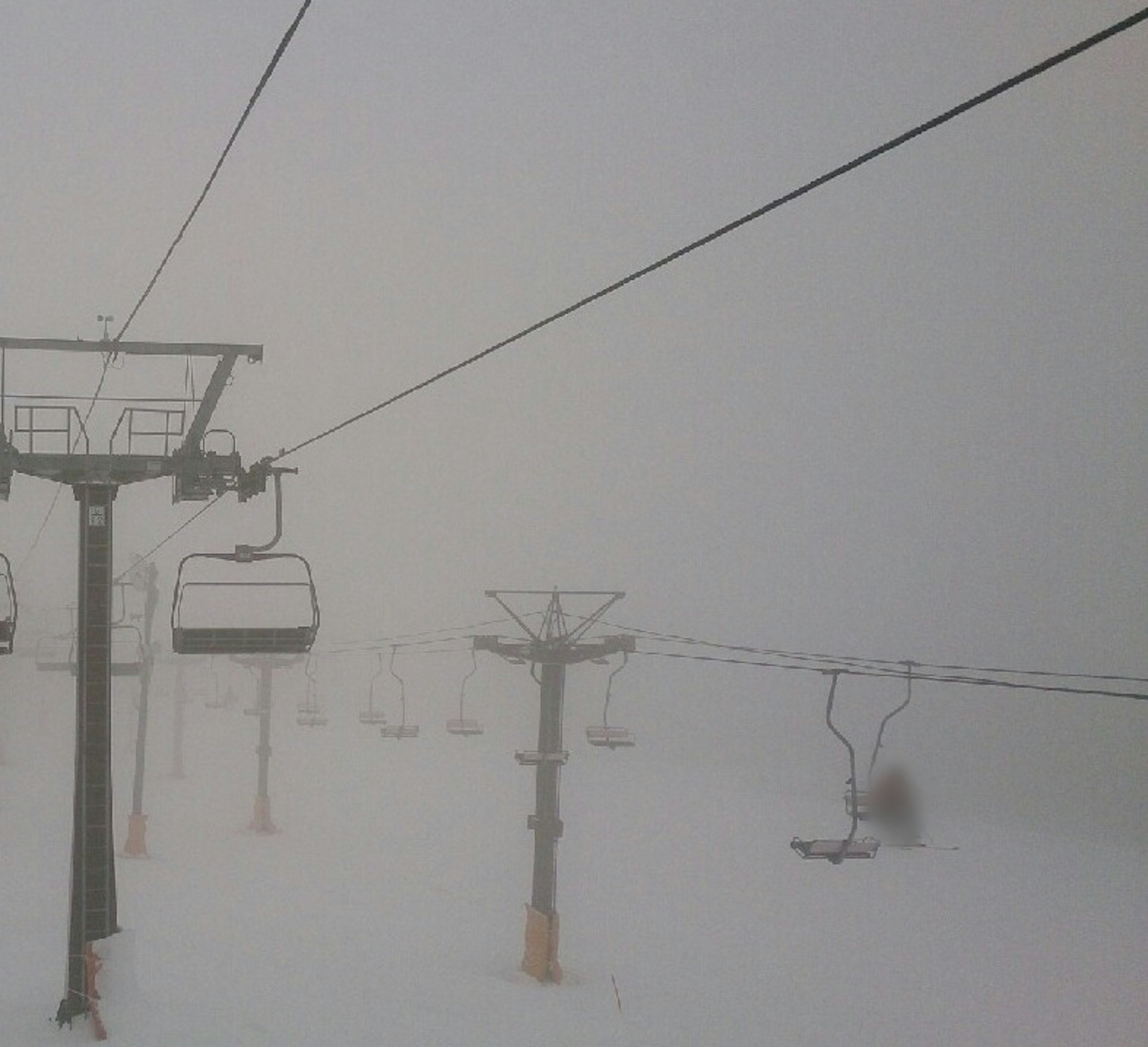 Escena de telesilla cubierta de nieve envuelta en niebla blanca