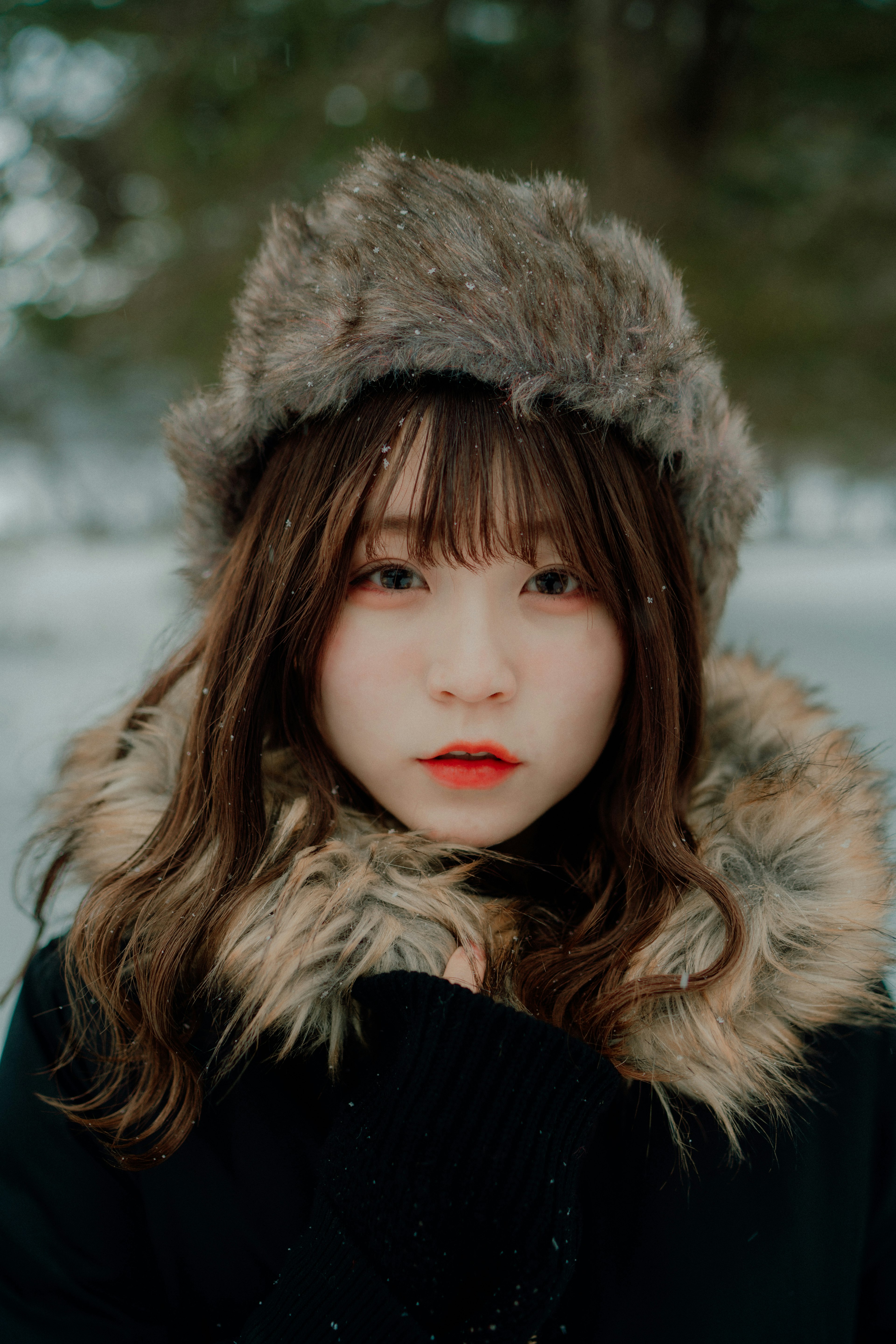 Portrait of a woman in the snow wearing a warm fur-lined coat and hat