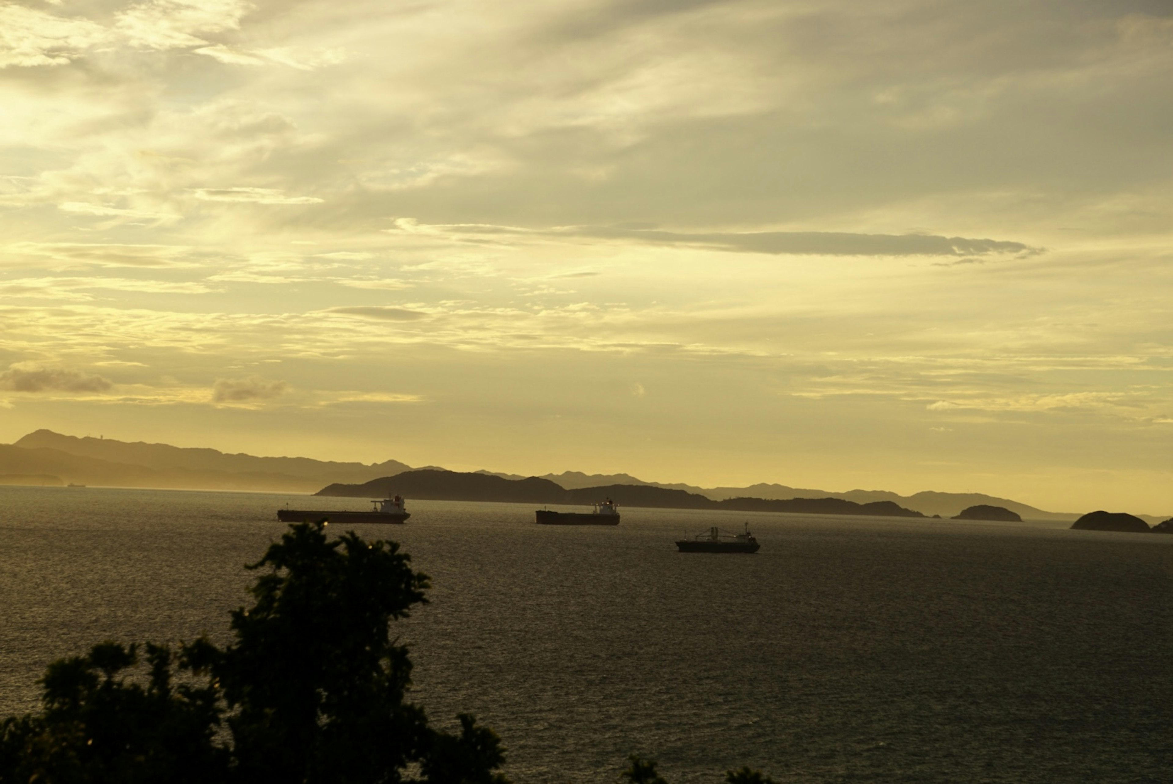 海と島々を背景にした夕暮れ時の景色に浮かぶ貨物船