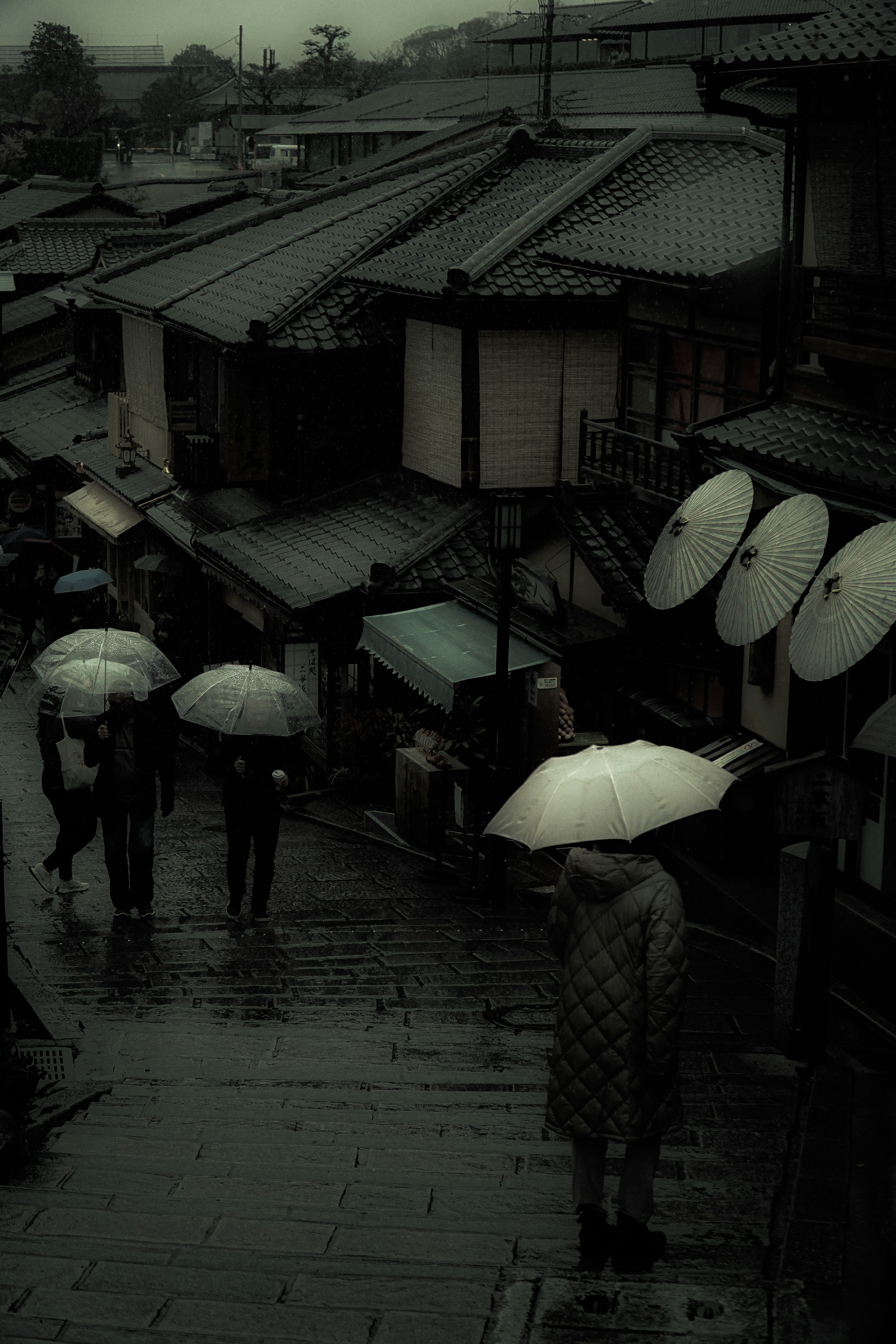 Menschen mit Regenschirmen in einer traditionellen japanischen Straße bei Regen