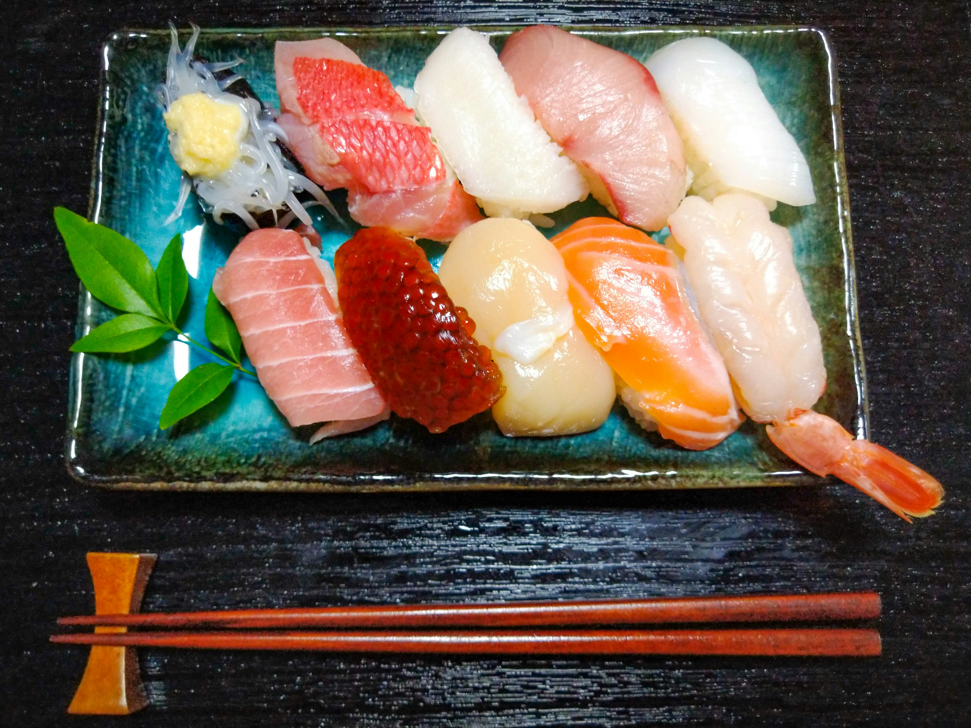 Piring biru yang menyajikan berbagai sushi yang berwarna-warni