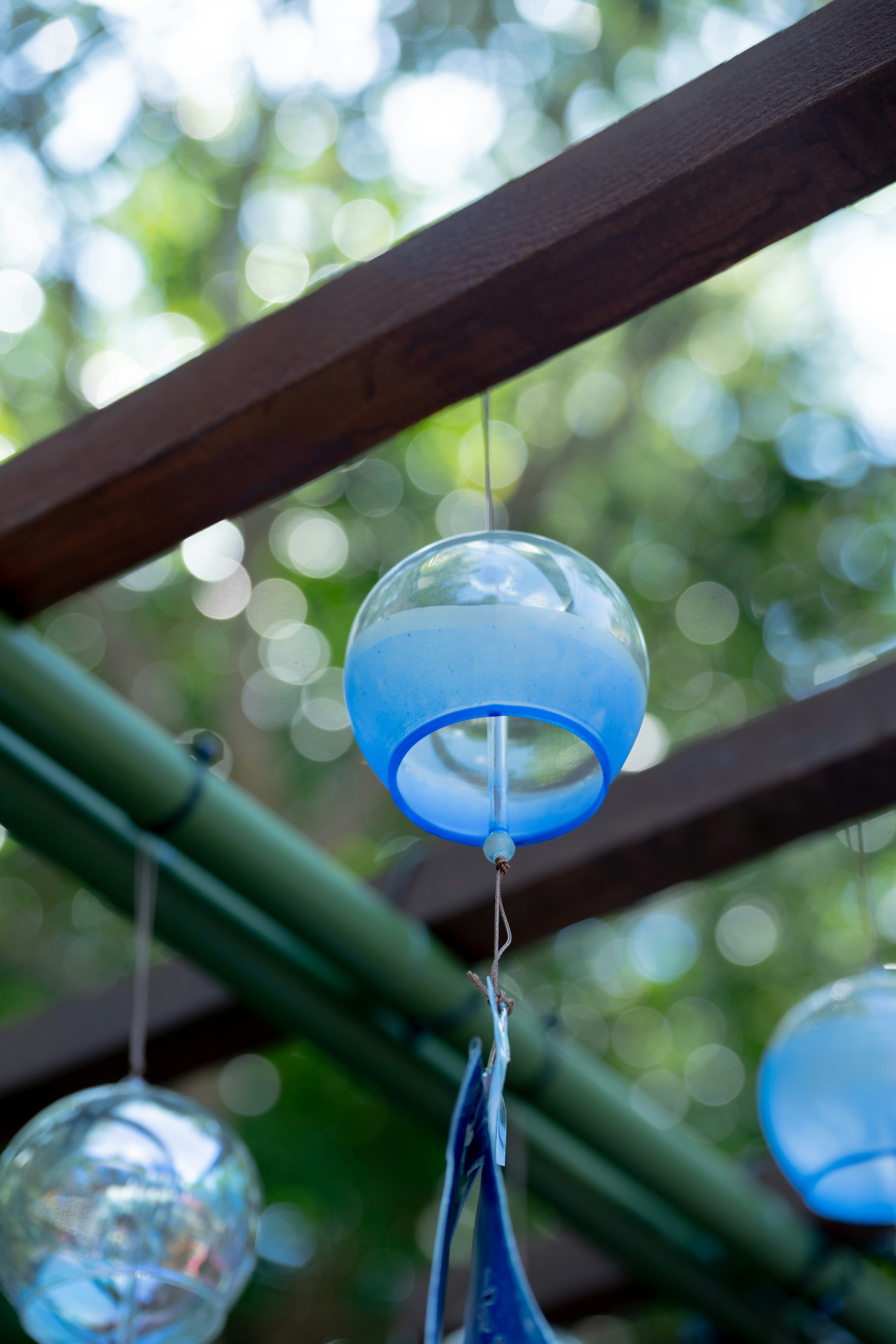 Blaues Windspiel, das an Holzträgern hängt