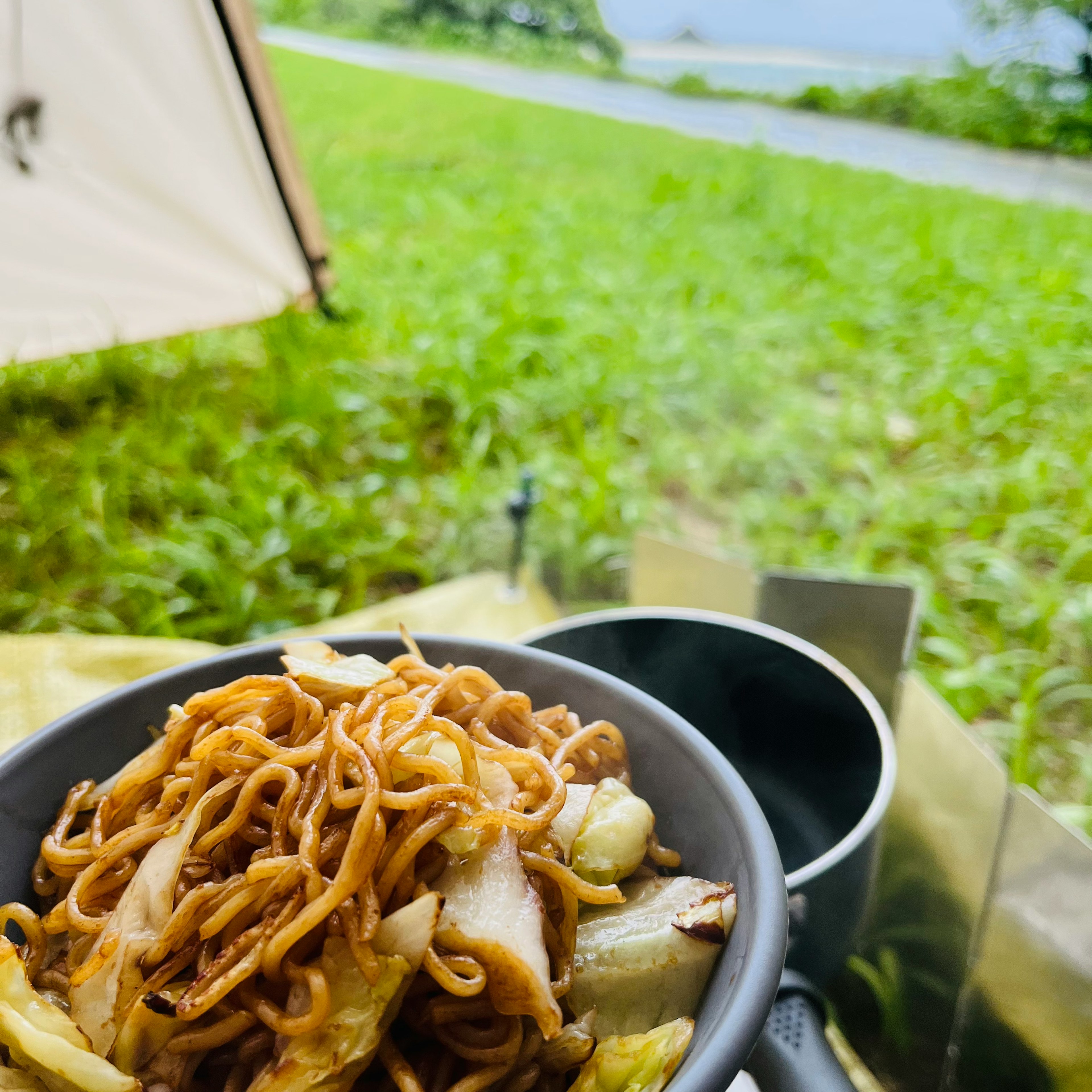 A bowl of stir-fried noodles with vegetables at a campsite