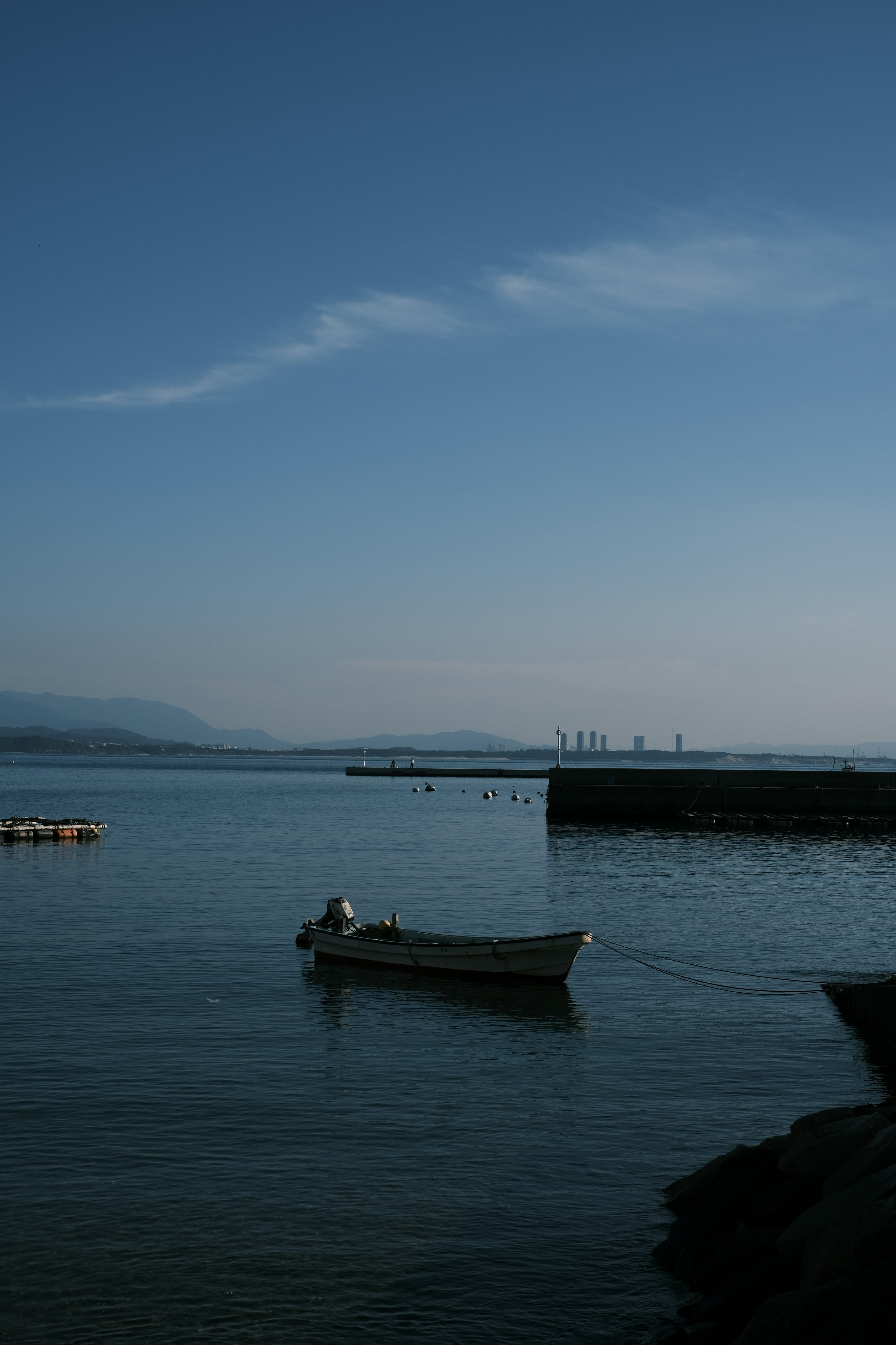 静かな海に浮かぶ小さなボートと遠くの港の風景