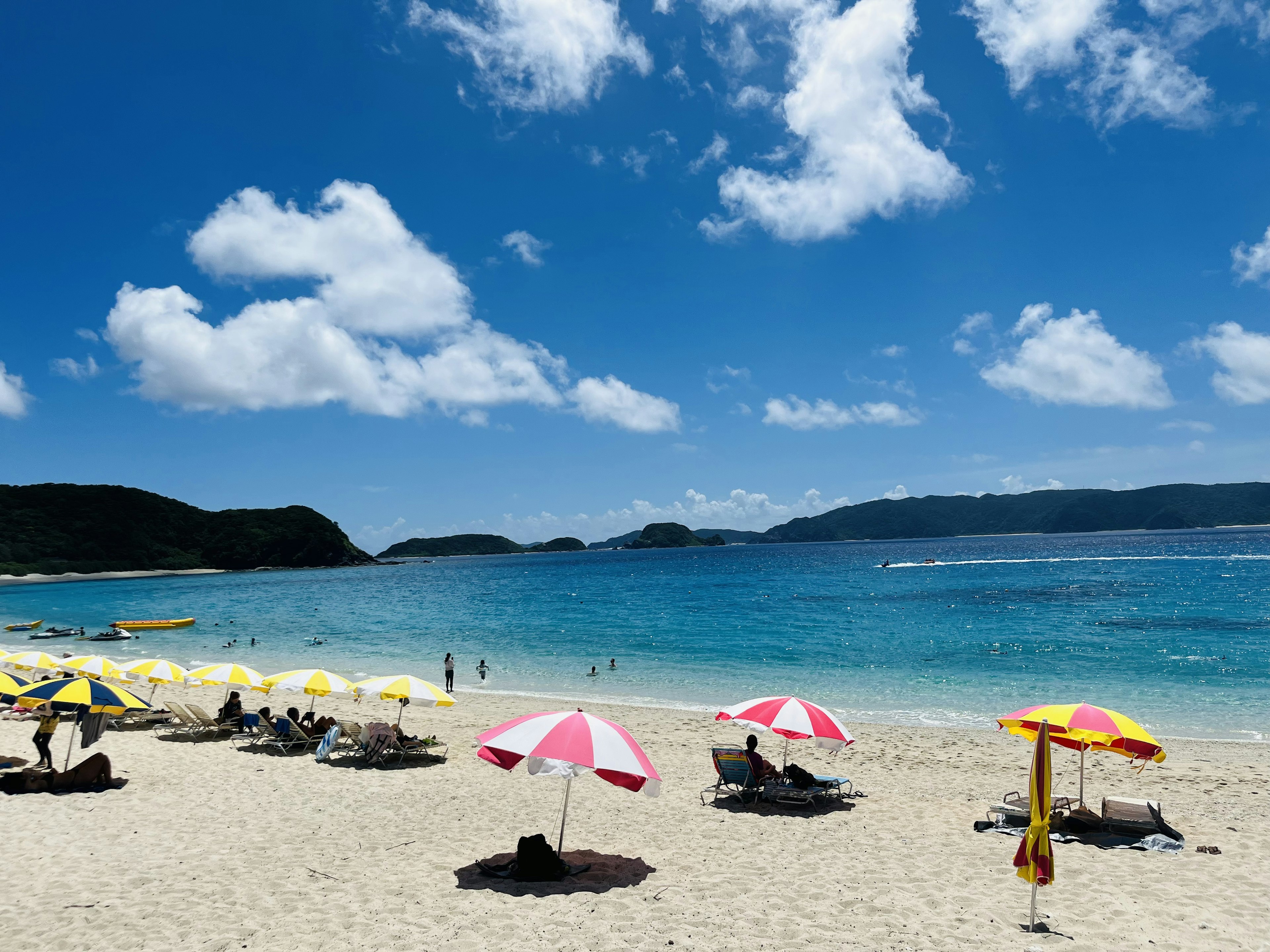 青い海と白い砂浜にビーチパラソルが並ぶリラックスした風景