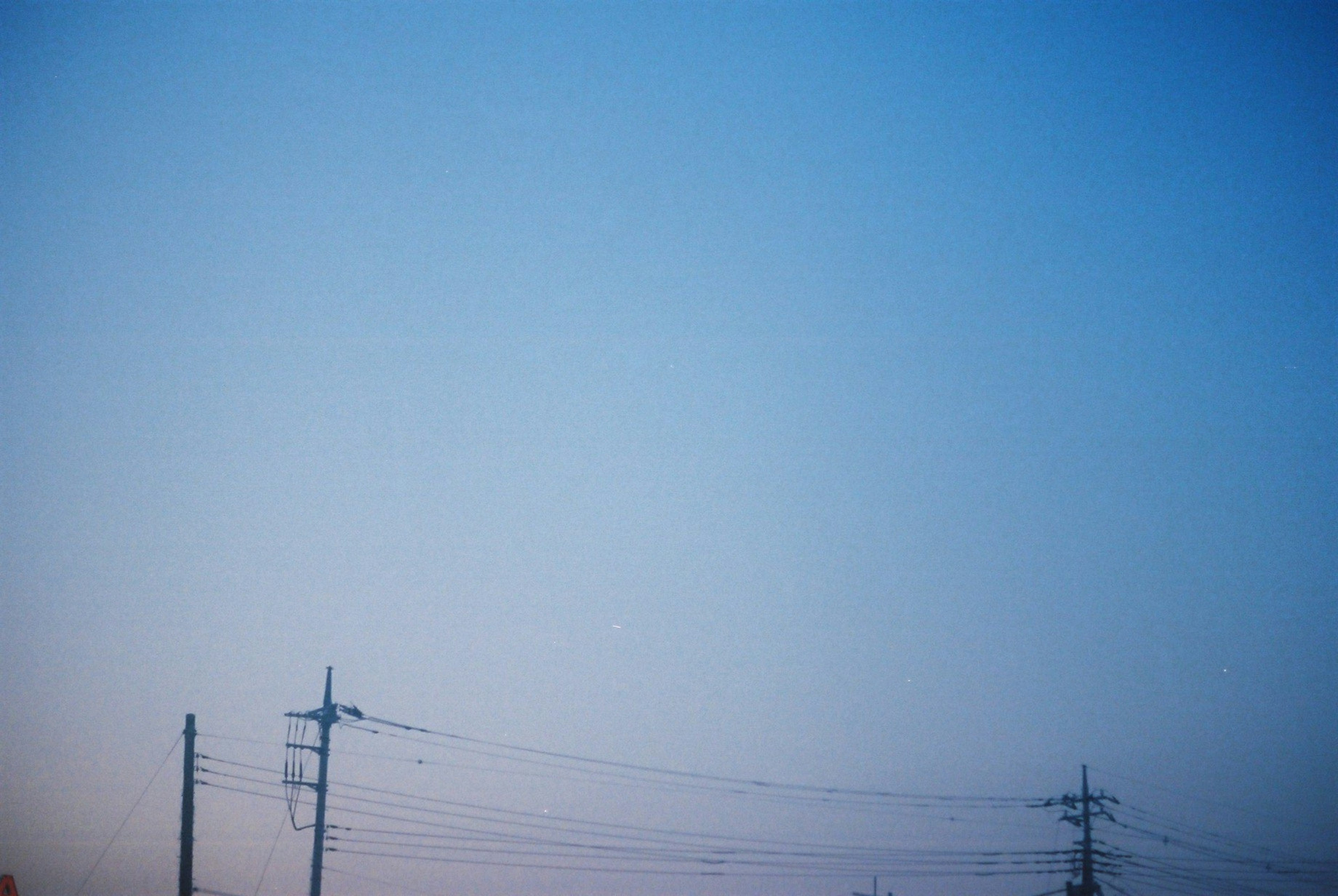 Ciel bleu avec des lignes et des poteaux électriques